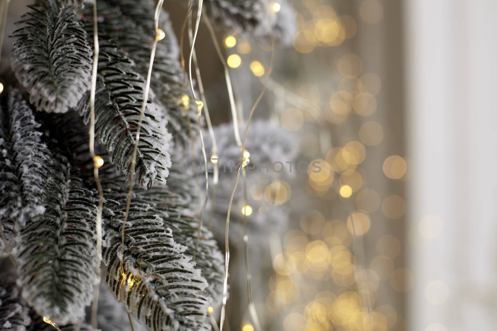 Christmas tree blur garland close-up New year background Decoration with snow and branch of Christmas tree