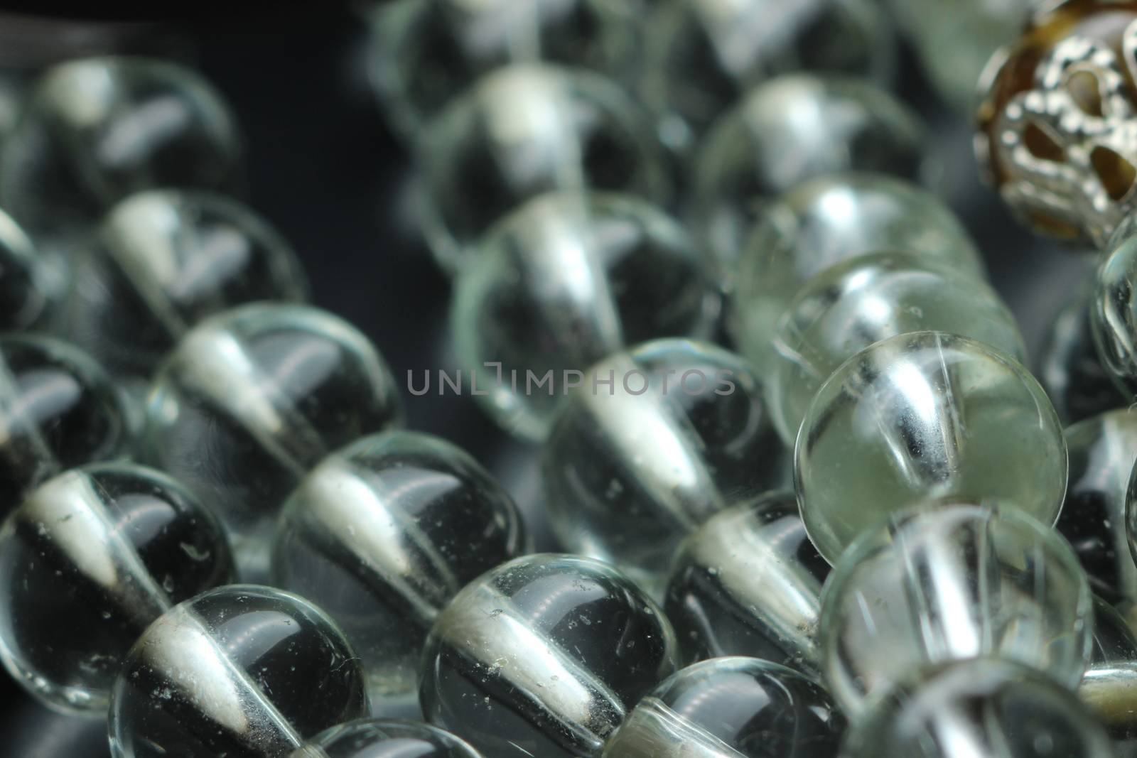 Macro photograph with selective focus of glass shiny prayer beads or rosary with copy space for text. Religion concept of ramadan or Eid for muslims.