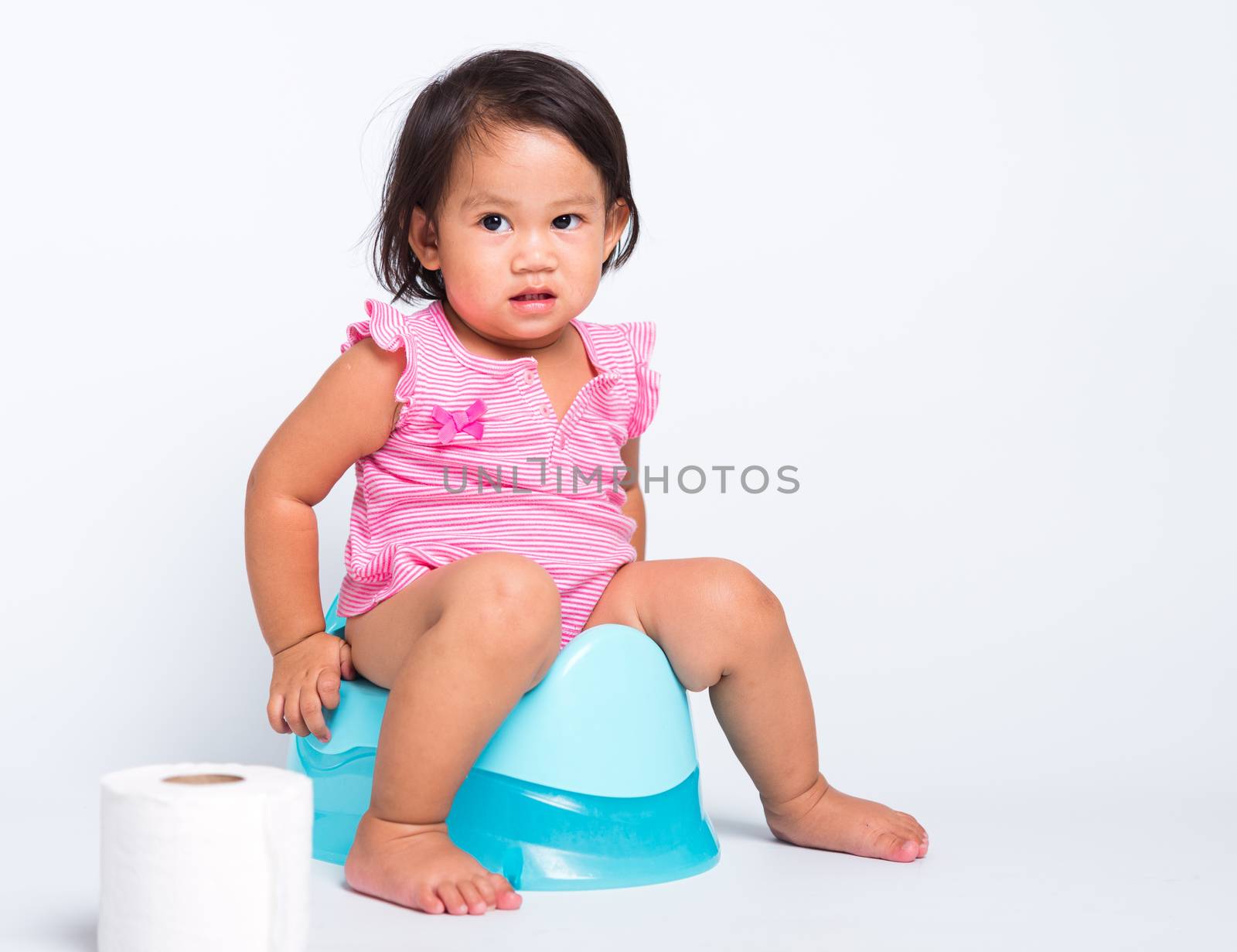 Asian little cute baby child girl education training to sitting on blue chamber pot or potty with toilet paper rolls, studio shot isolated on white background, wc toilet concept