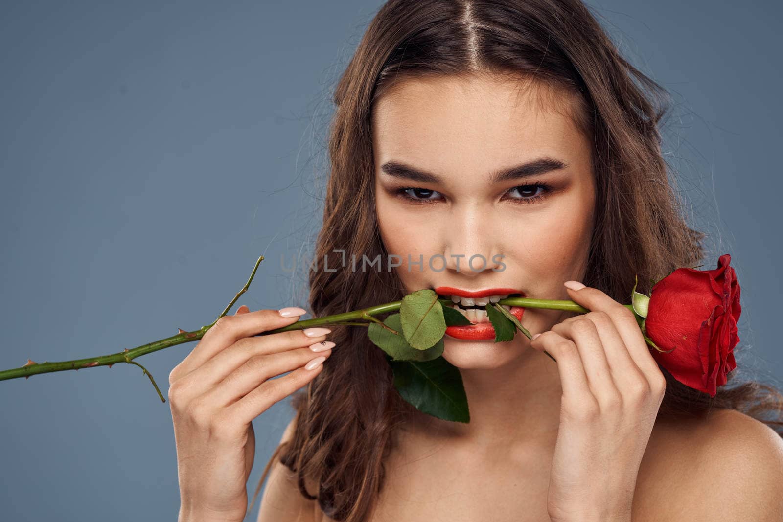 woman with a rose in her hands naked shoulders evening makeup red lips. High quality photo