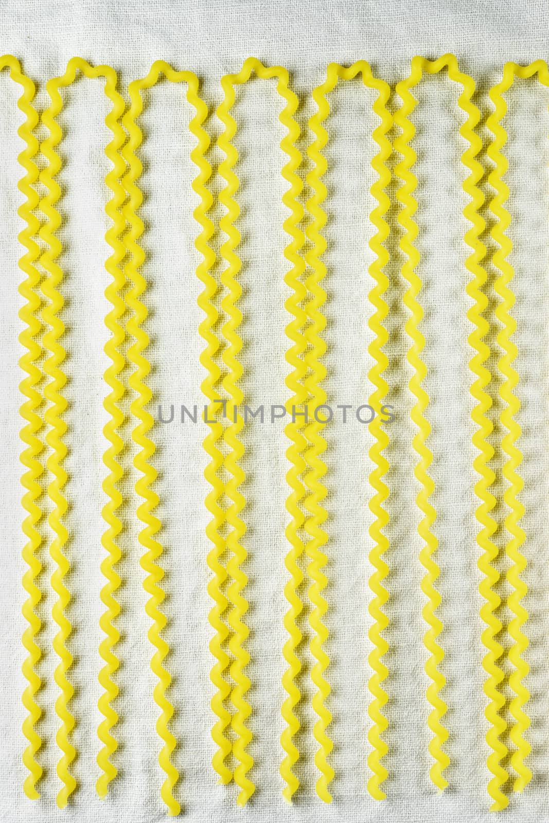 Raw Italian pasta called fusilli  , long thin corkscrew shaped pasta on a white cotton cloth