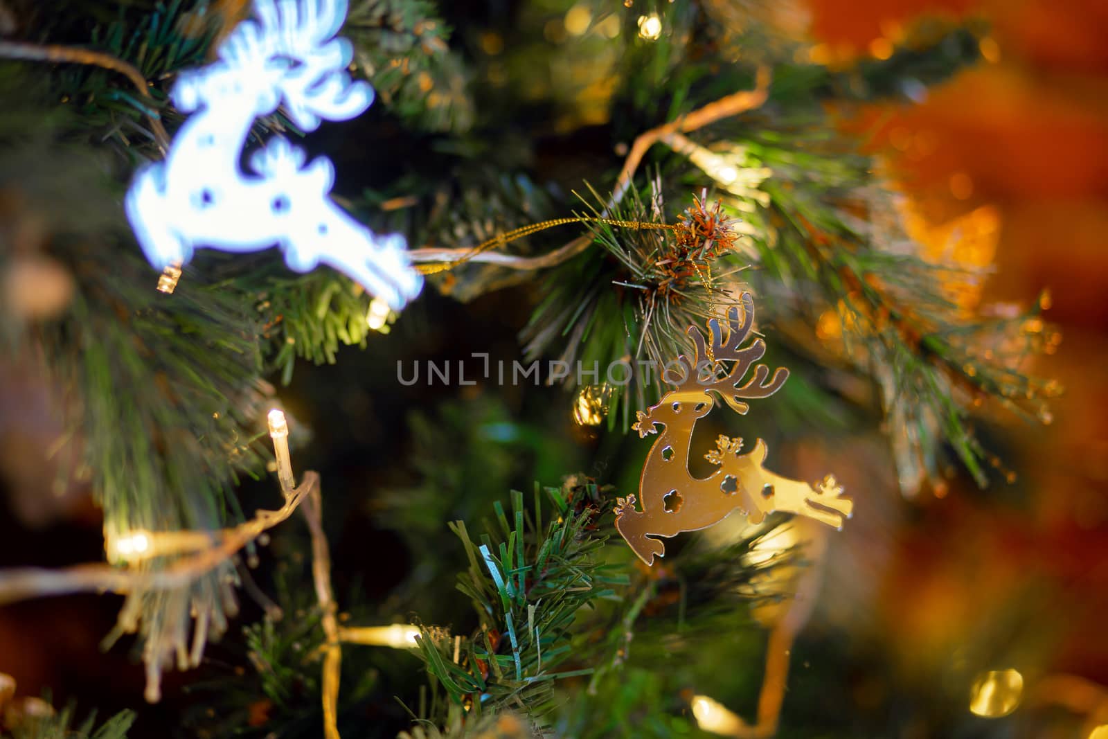 Christmas decoration in the form of a galloping deer on a Christmas tree. Golden deer, Christmas tree toy on a branch of a festive tree