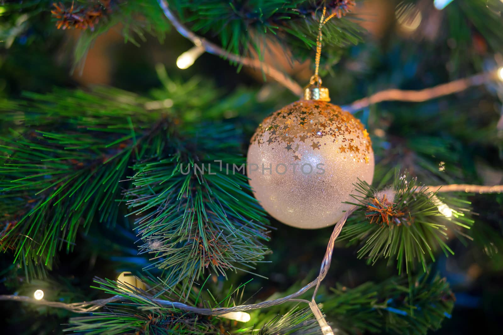 golden ball hanging on a branch of a christmas tree. Christmas tree decoration. Preparing for the holiday, garland