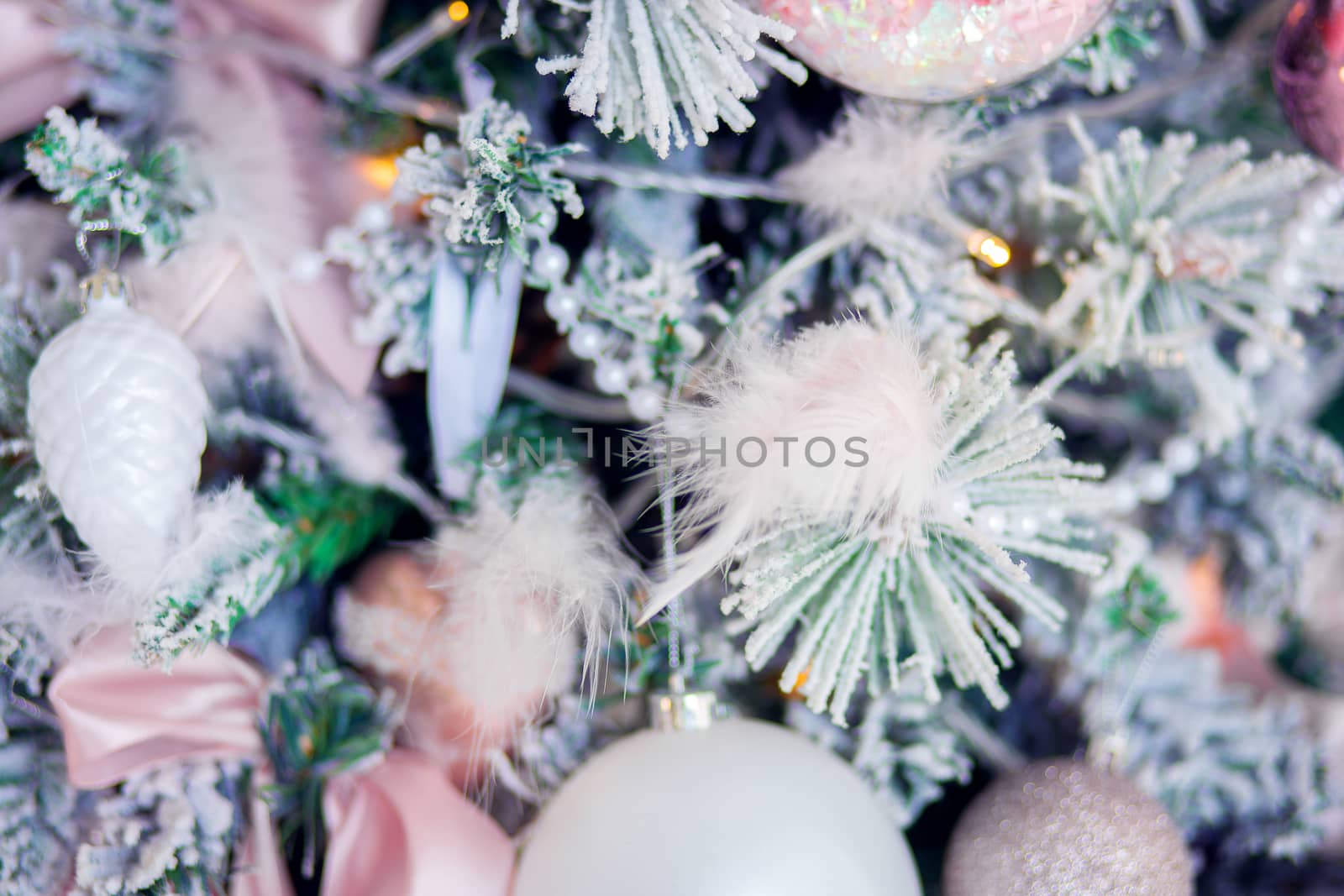 Christmas tree decoration close-up. Christmas tree decor elements in gentle trendy colors. Background for postcards. Decorating the tree with feathers