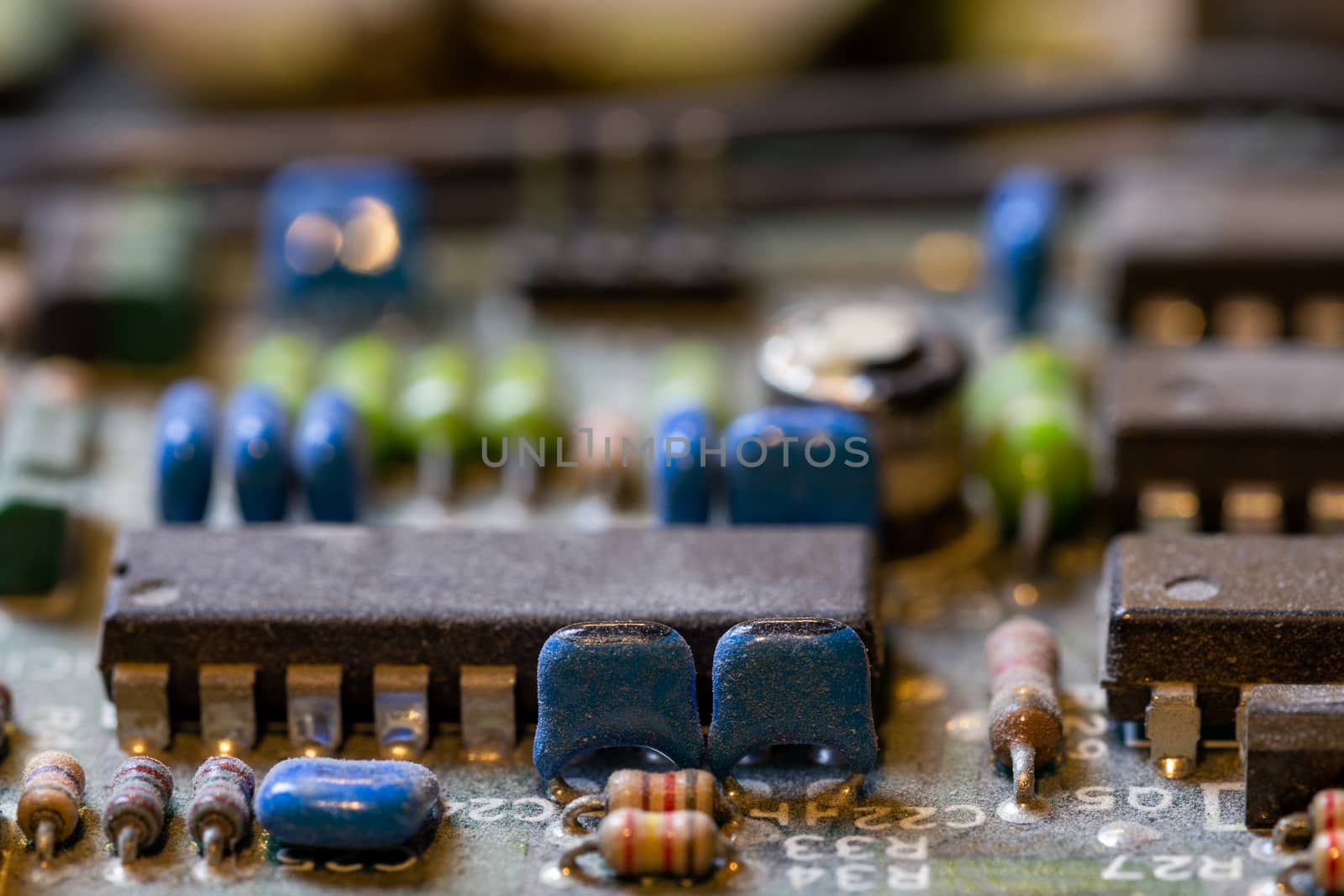 background of old electronic circuit board closeup in dark colors with dust and selective focus