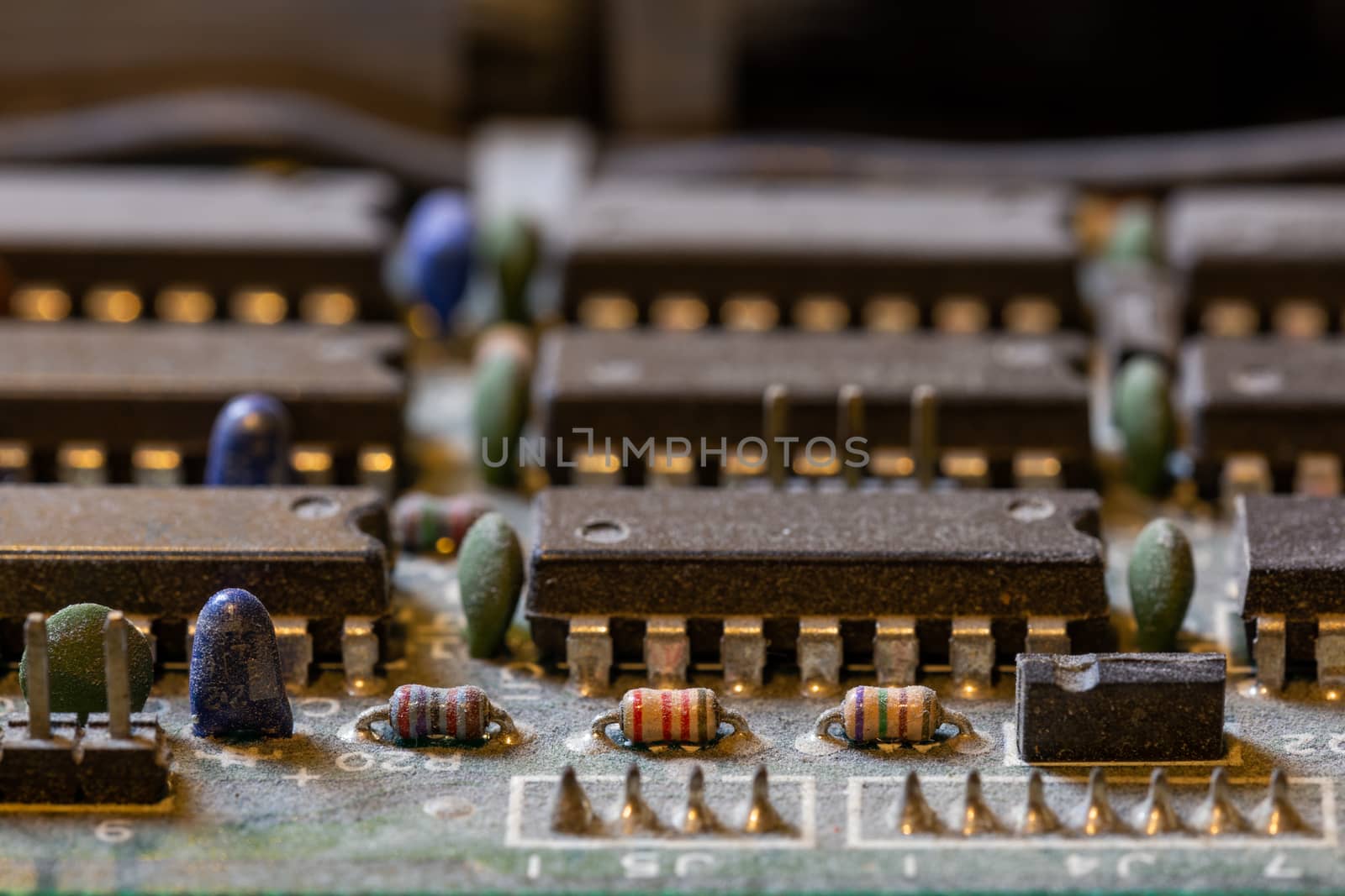 background of old electronic circuit board closeup in dark colors with dust and selective focus