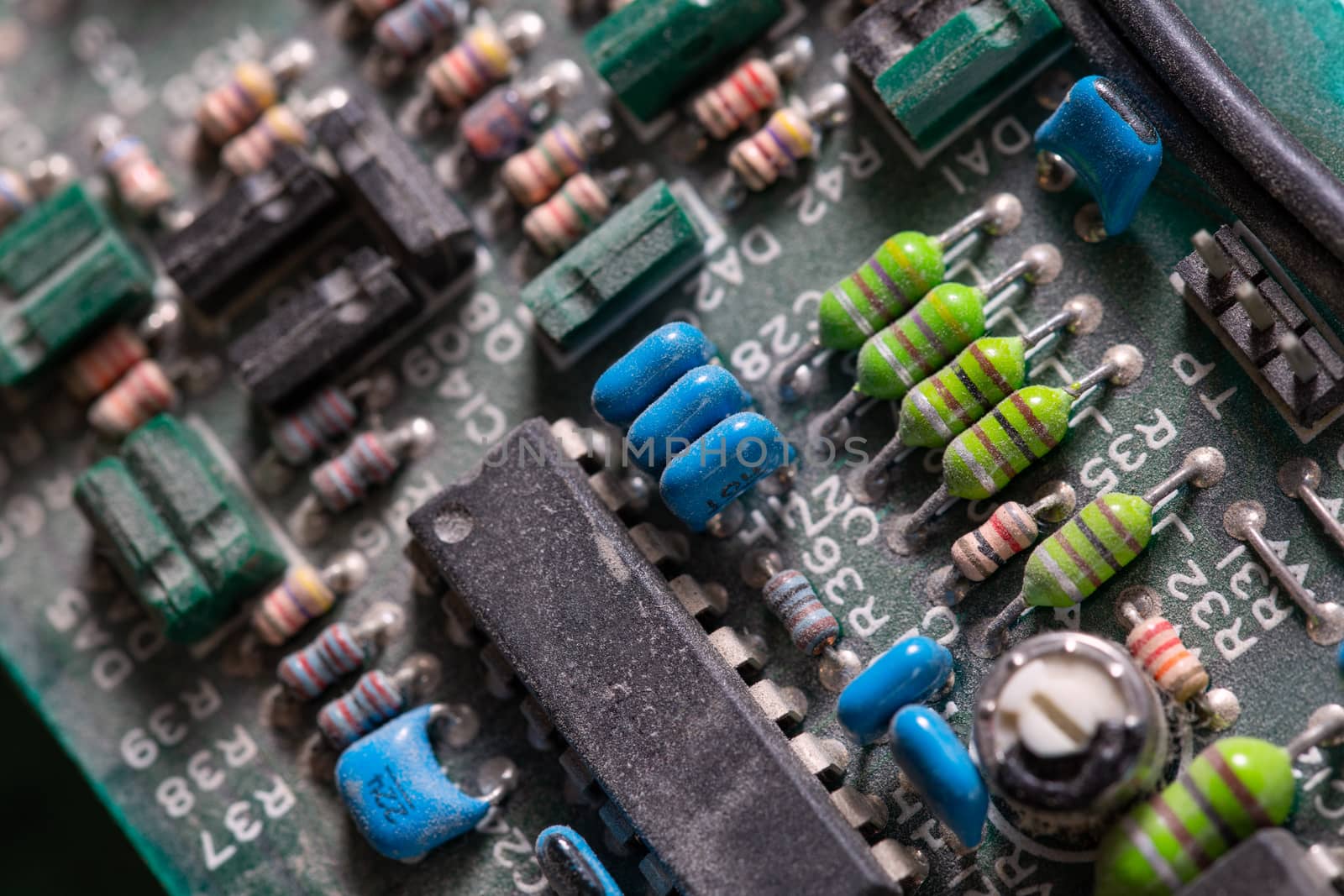 background of old electronic circuit board closeup in dark colors with dust and selective focus