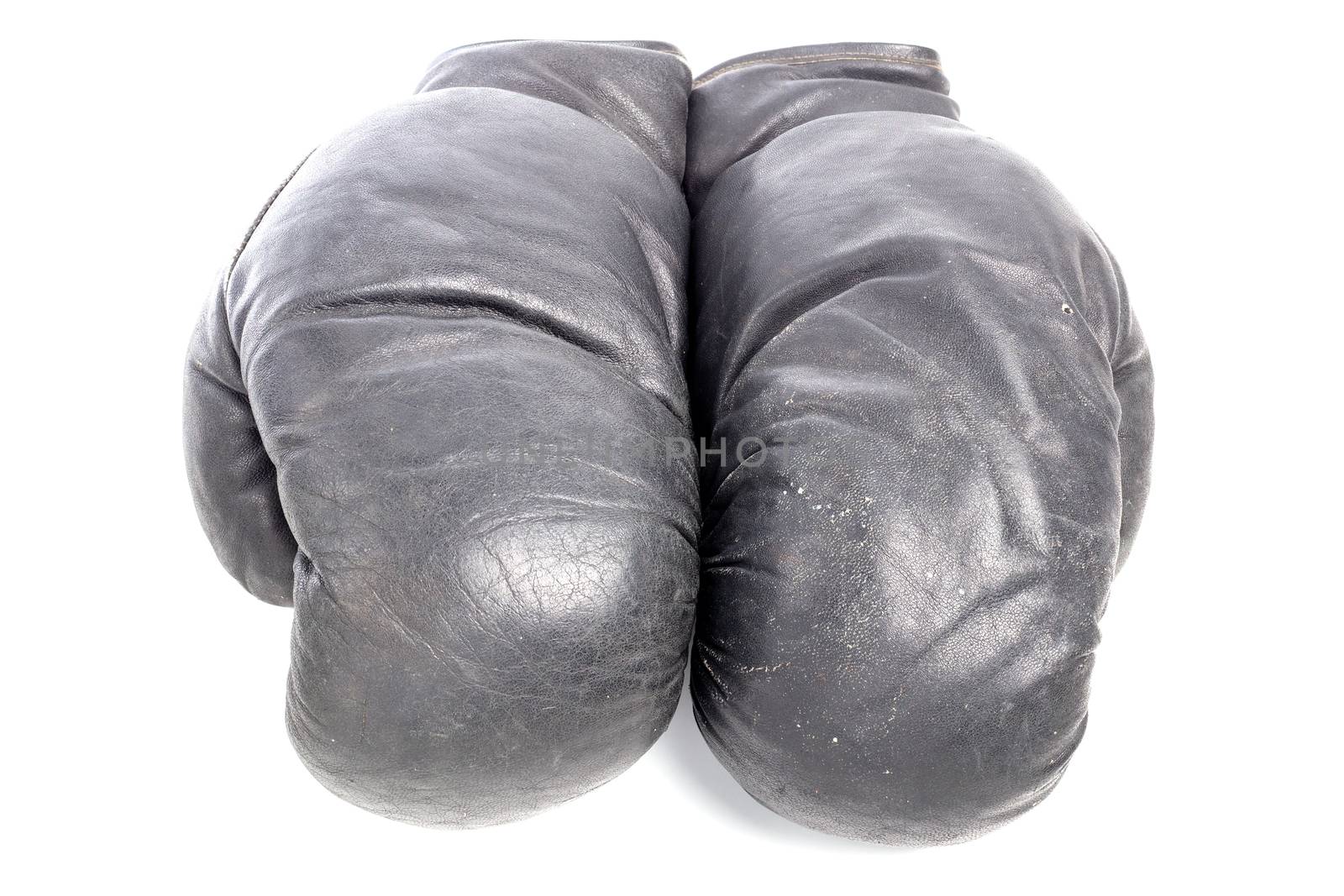 Old black leather boxing gloves isolated on white background with shadows lying on flat surface. Horsehair stuffed.
