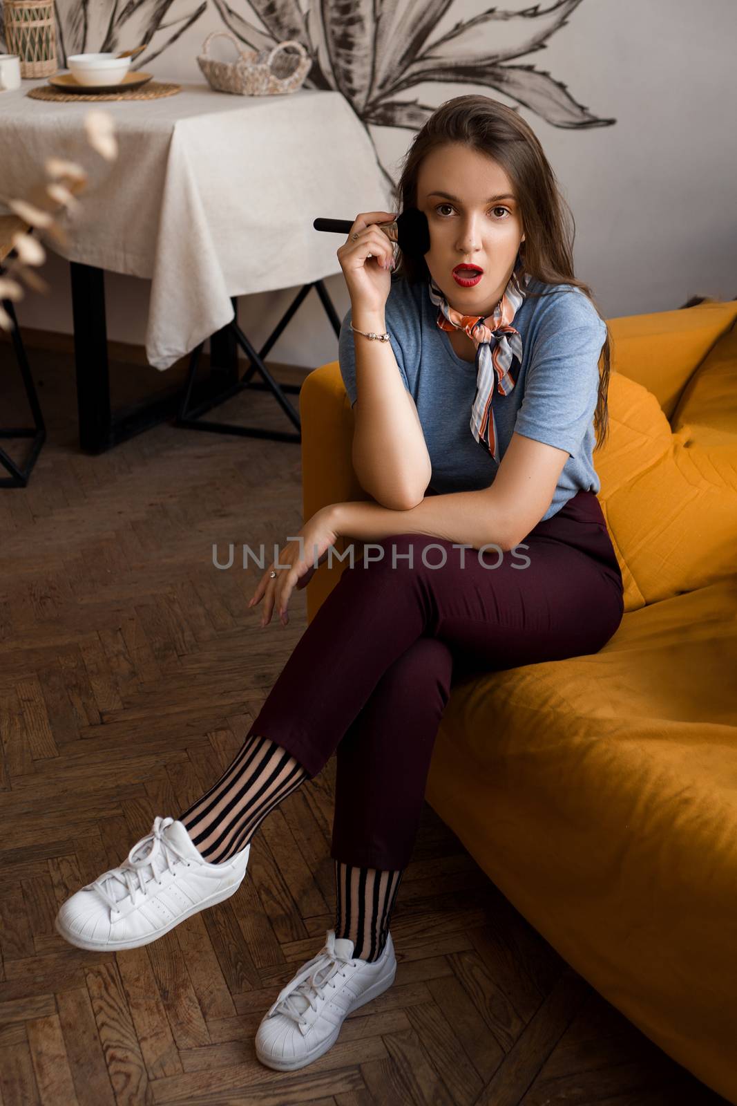 Make-up artist with brushes sitting on the couch in cozy interior