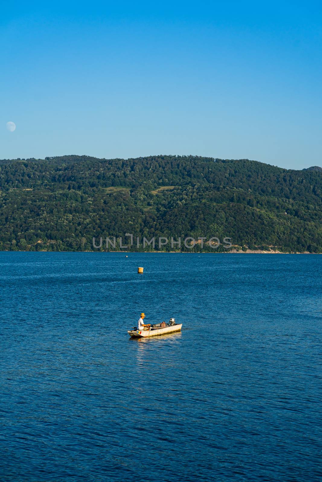 Man in boat relaxing and fishing on Danube river on a sunny day in Orsova, Romania, 2020.