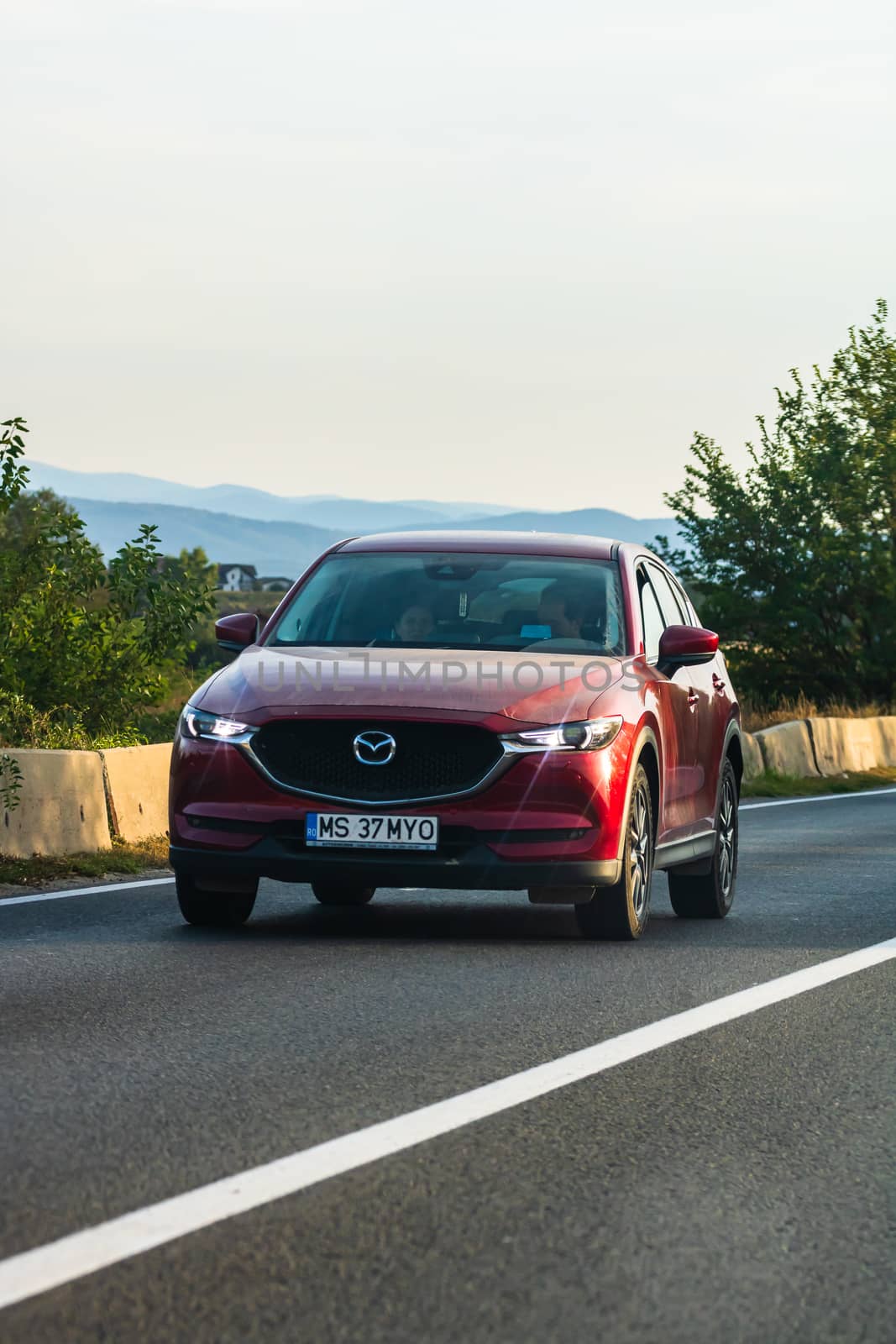 Traveling red Mazda car in motion on asphalt road, front view of by vladispas