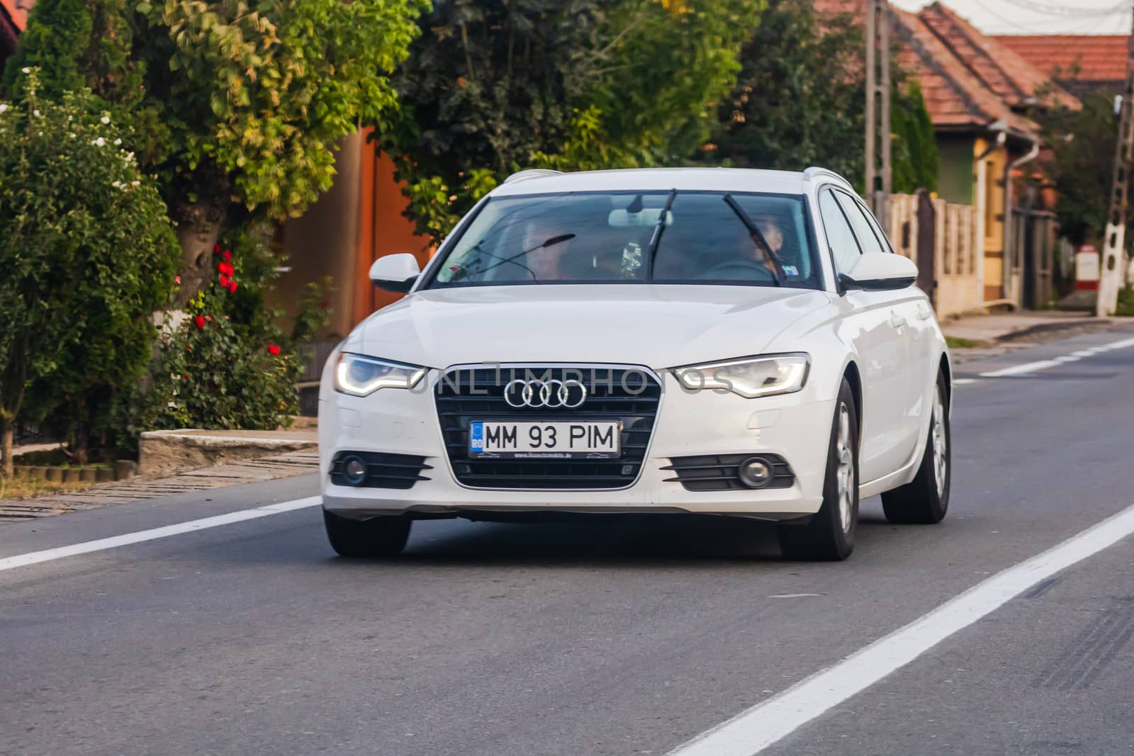 Traveling white Audi car in motion on asphalt road, front view o by vladispas