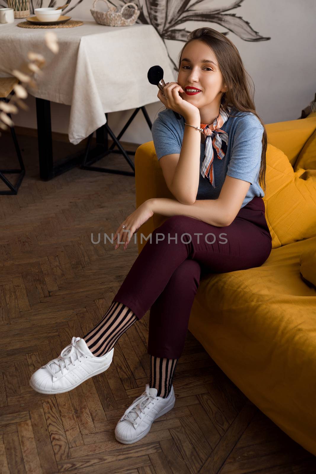Make-up artist with brushes sitting on the couch in cozy interior