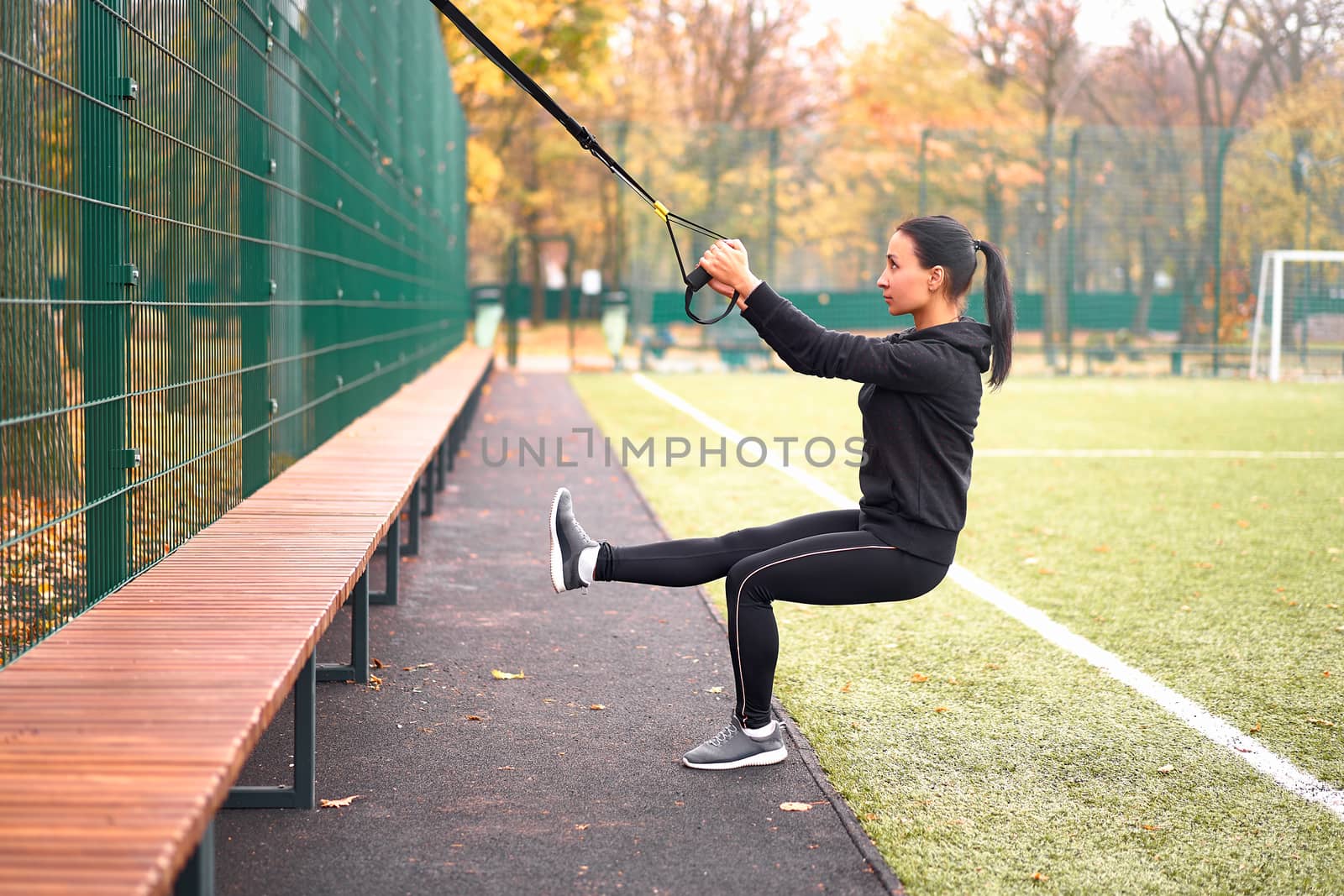 Girl athlete training using trx sportground Mixed race young adult woman workout suspension system Healthy lifestyle Stretching outdoors playground. Make your body machine