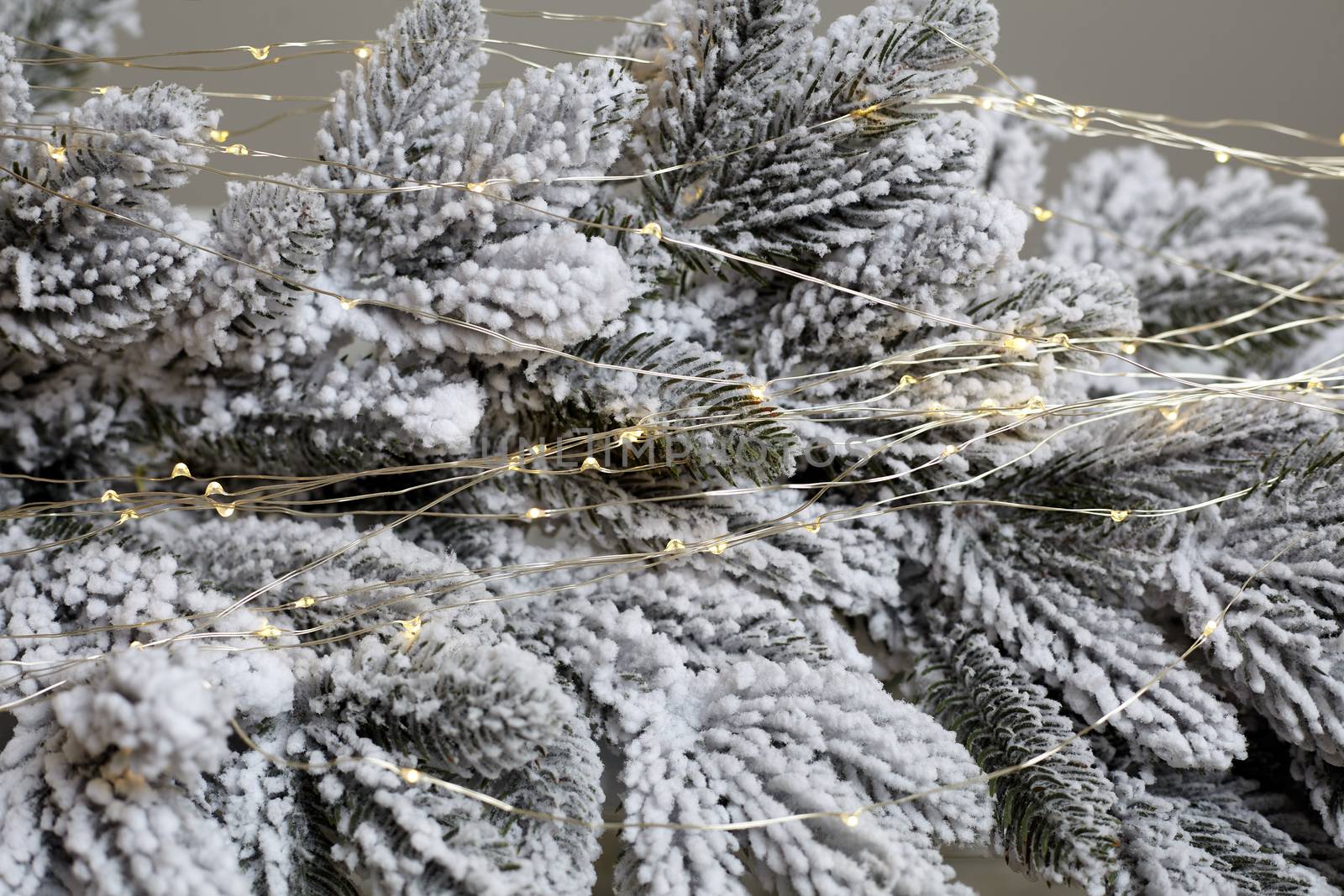 Christmas tree blur garland close-up New year background Decoration with snow and branch of Christmas tree