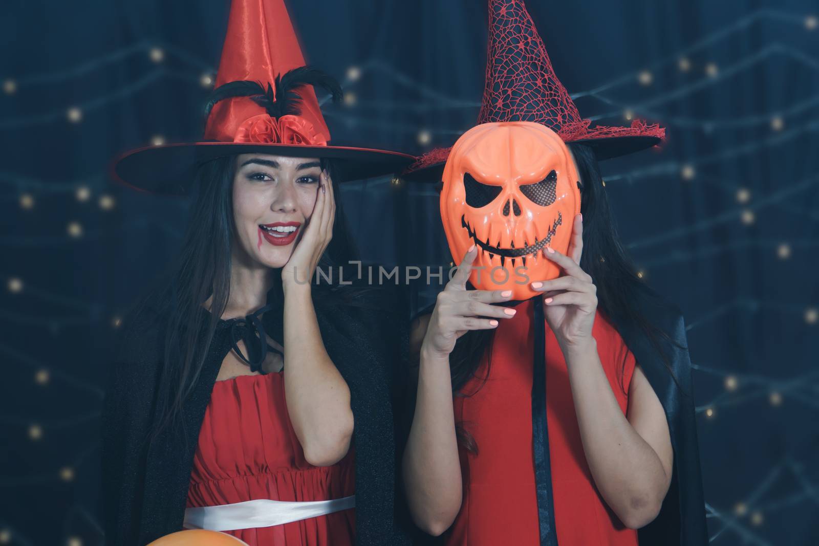 Beautiful Caucasian women and friends dressed up in Halloween witch costumes. Attractive young woman holding a carved pumpkin mask and Have fun at a party Halloween Celebration