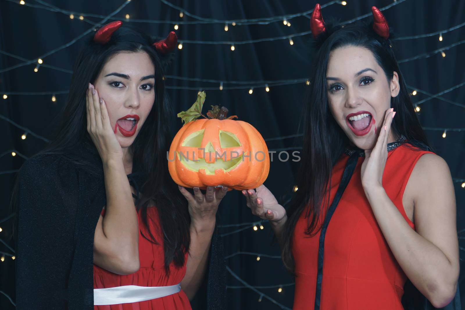 Beautiful Caucasian women and friends dressed up in Halloween witch costumes. Attractive young woman holding a carved pumpkin and Have fun at a party Halloween Celebration