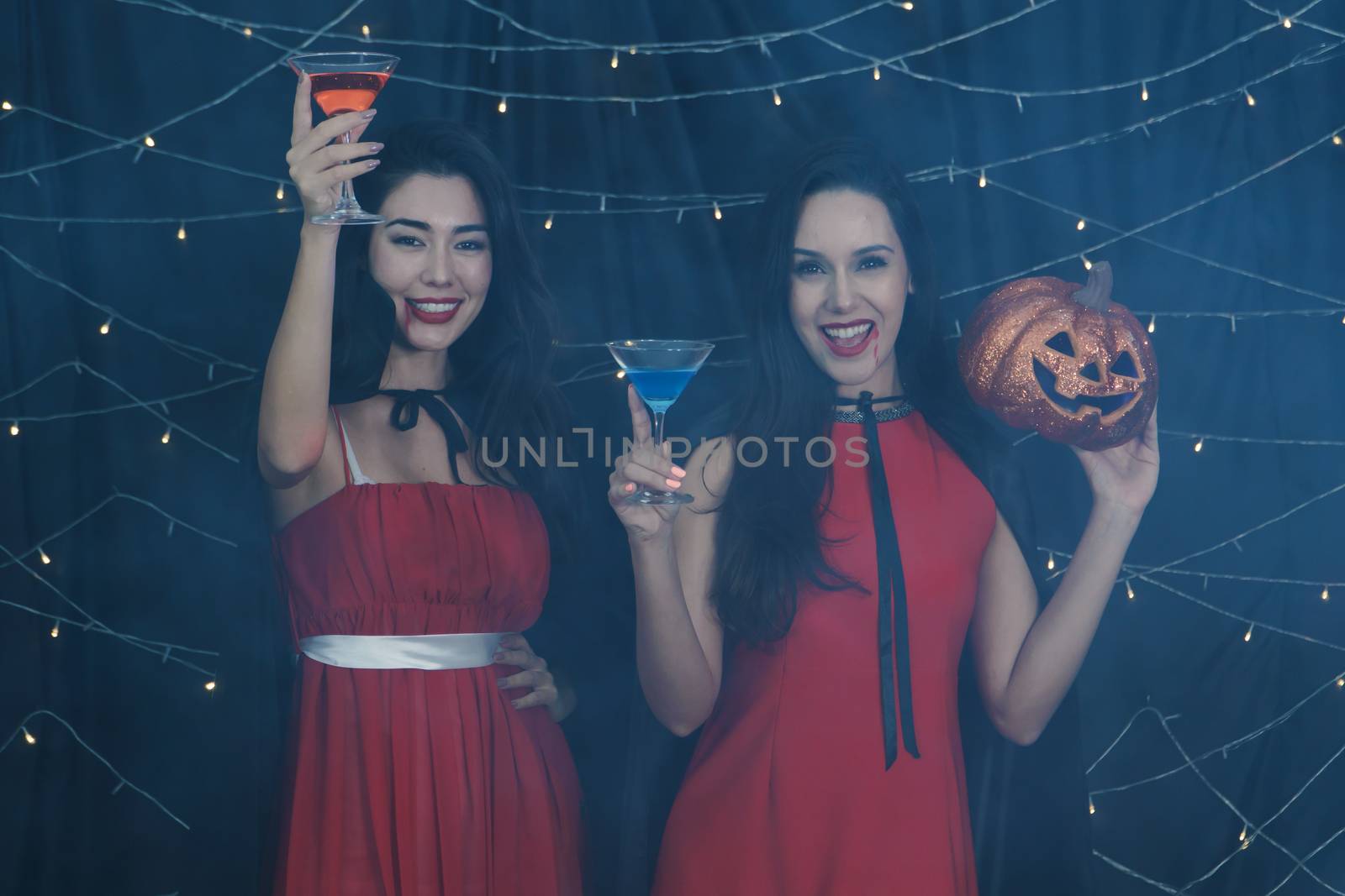 Beautiful Caucasian women and friends dressed up in Halloween witch costumes. Attractive young woman holding a pumpkin carving and drinking Cocktails. Have fun at a party  Halloween celebration