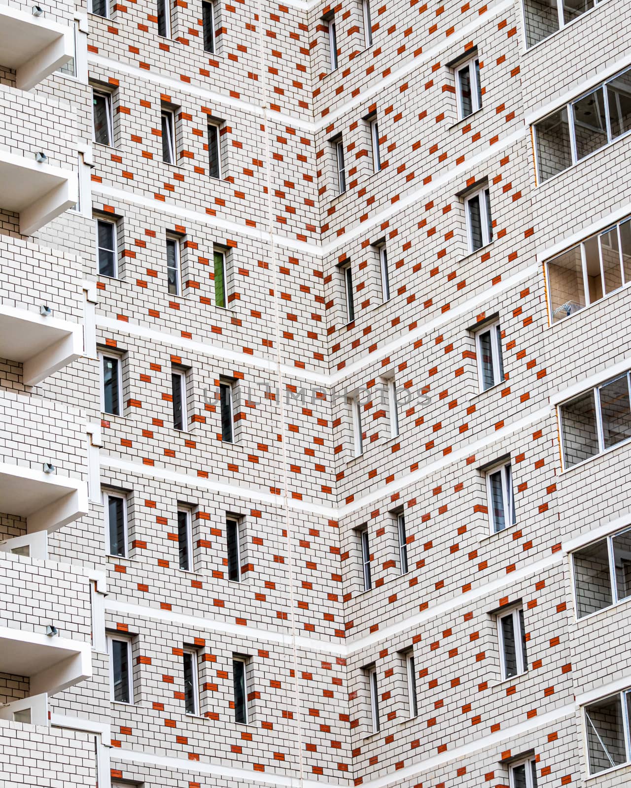 Fragment of a white brick residential building with balconies.