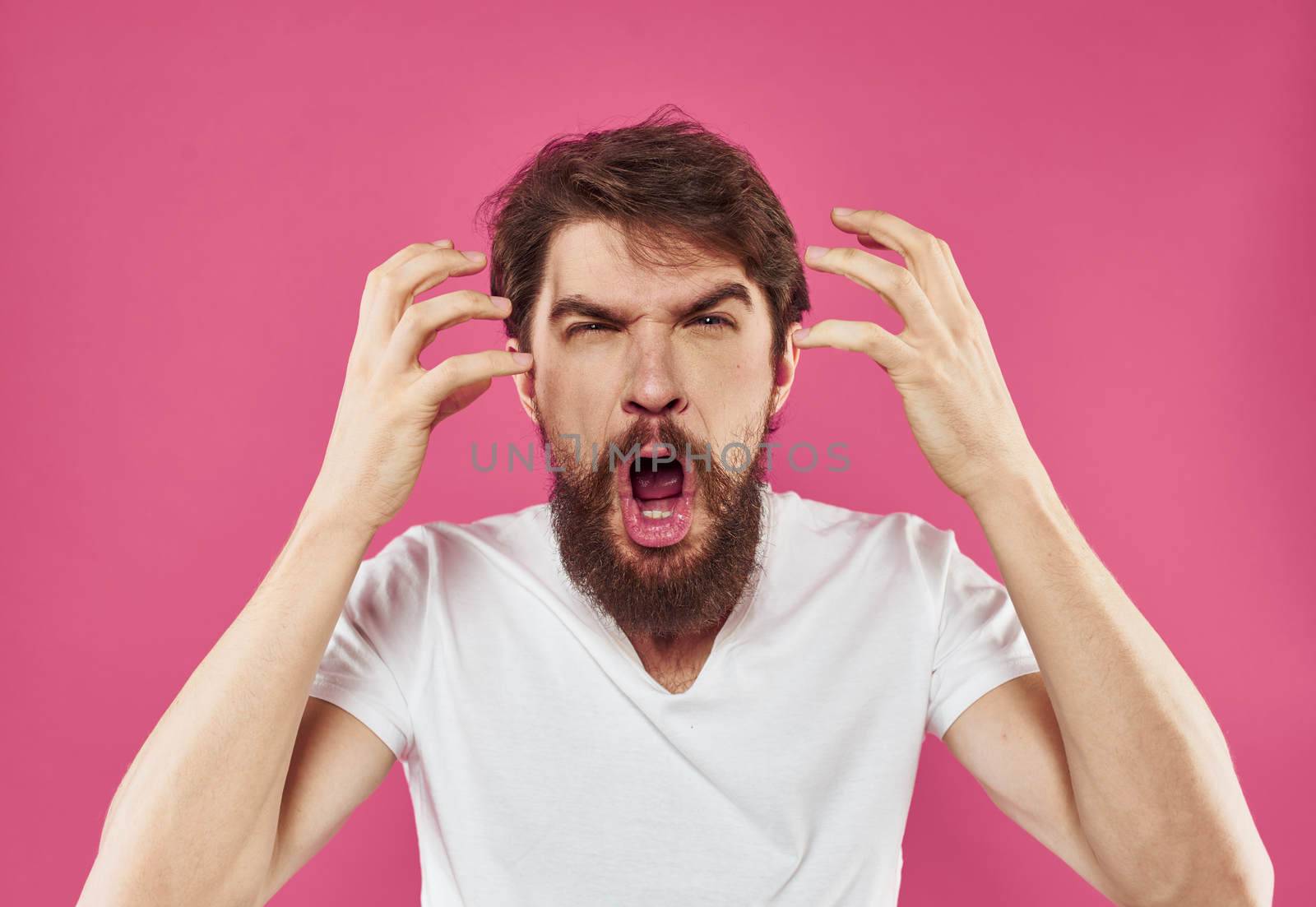 Angry man yells on pink background stress irritability model. High quality photo