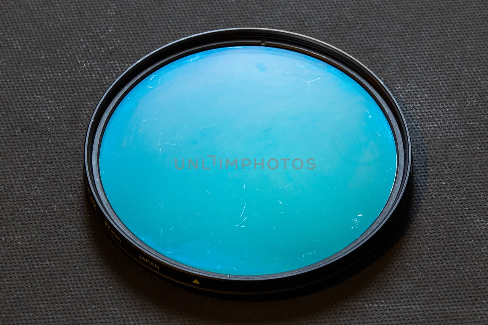 old rotary polarizing filter with scratches on dark background.