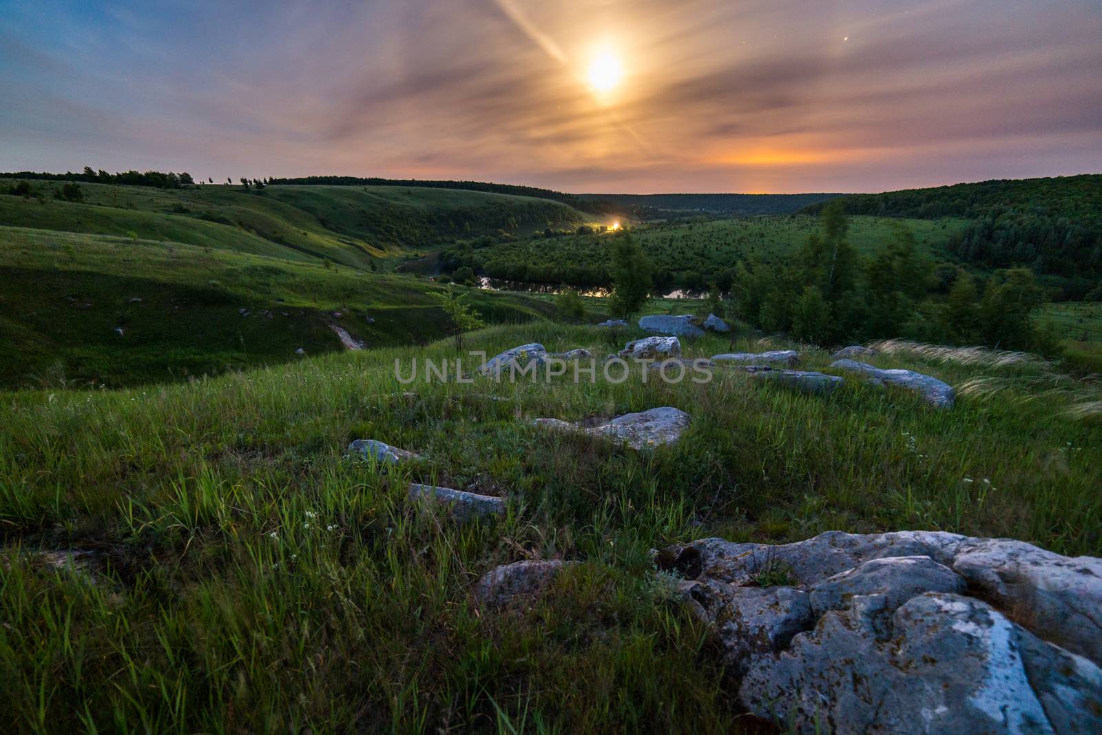 night glacial stones in field landscape under moonlight halo