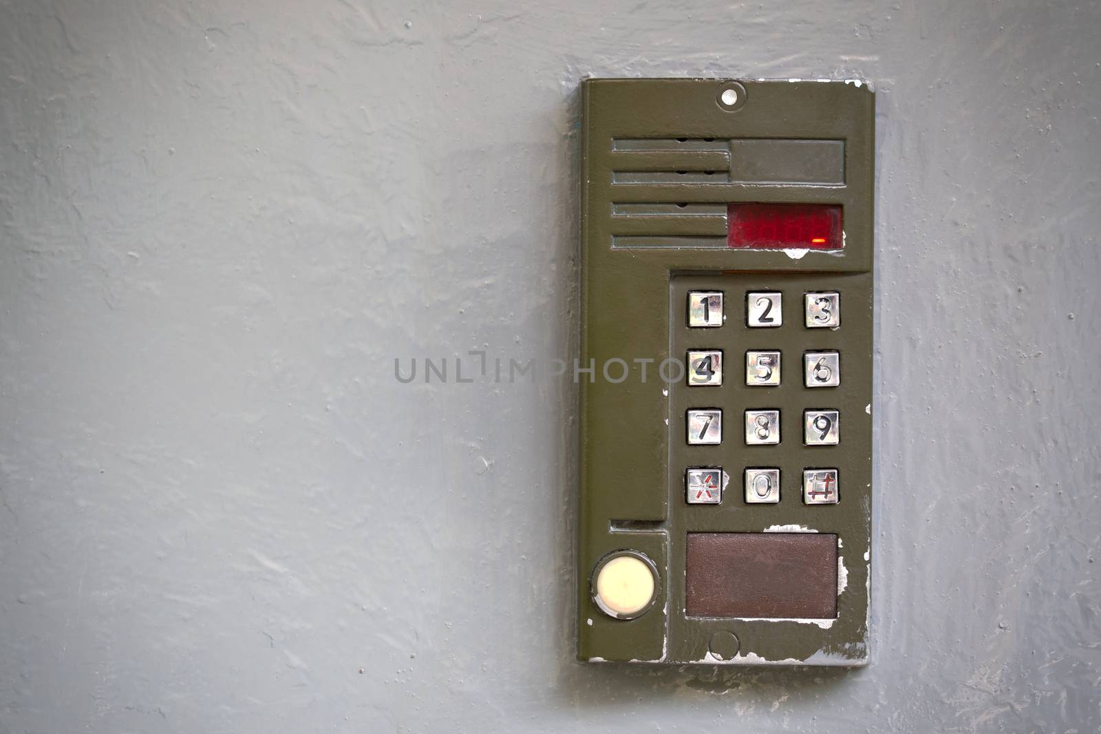 Old digital doorphone with silver buttons on gray oil painted flat surface