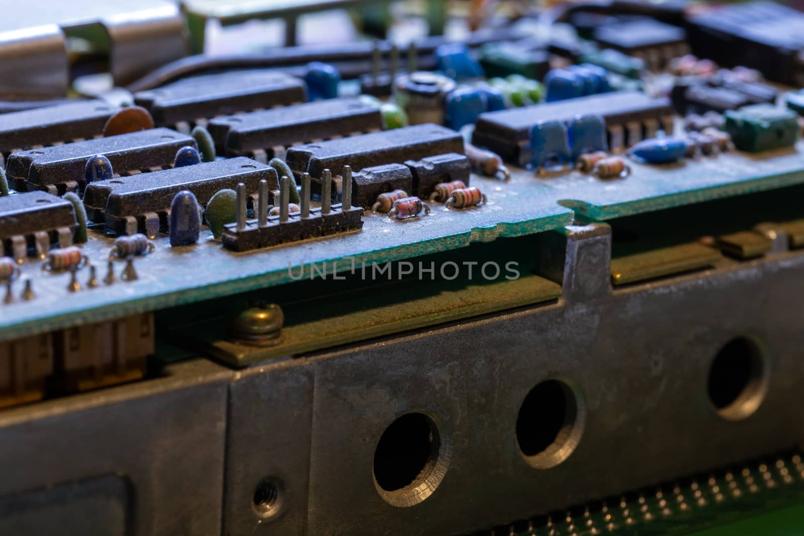 background of old electronic circuit board closeup in dark colors with dust and selective focus