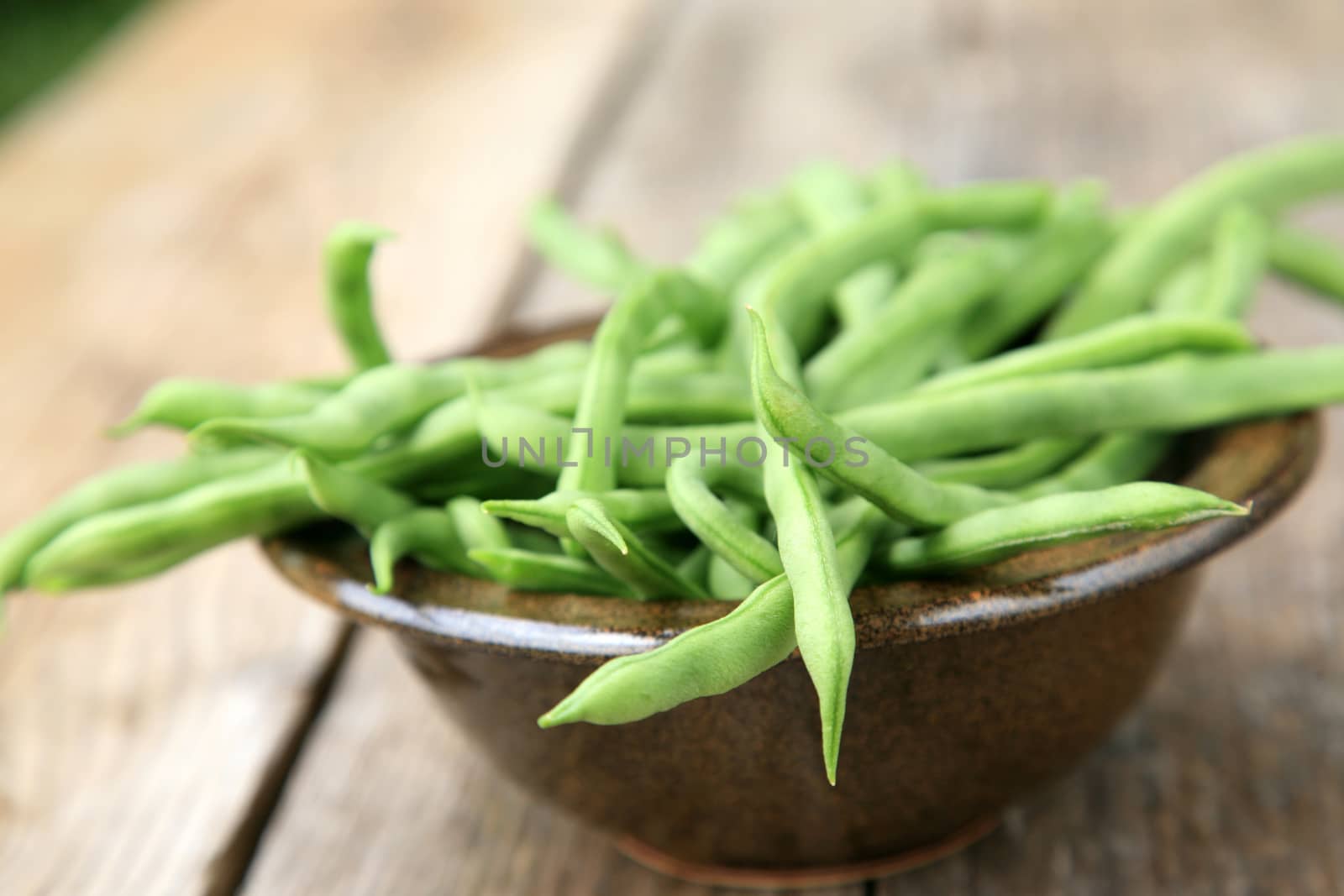 Many green beans in a brown bowl