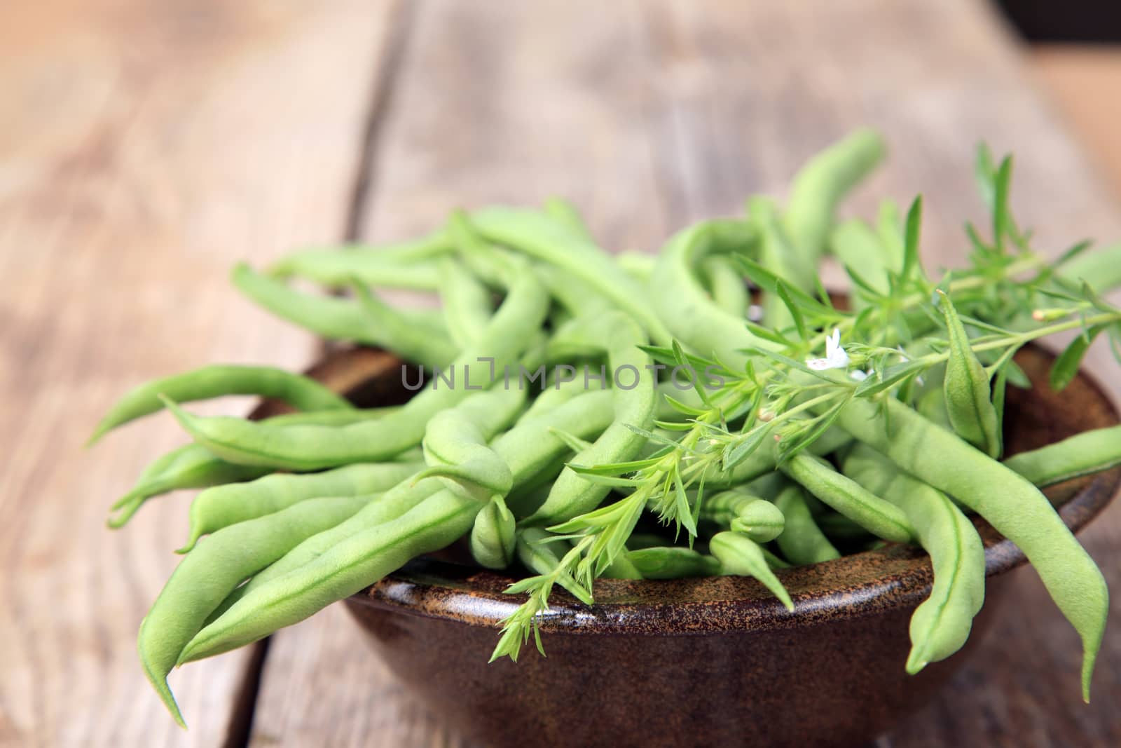 Many green beans in a brown bowl