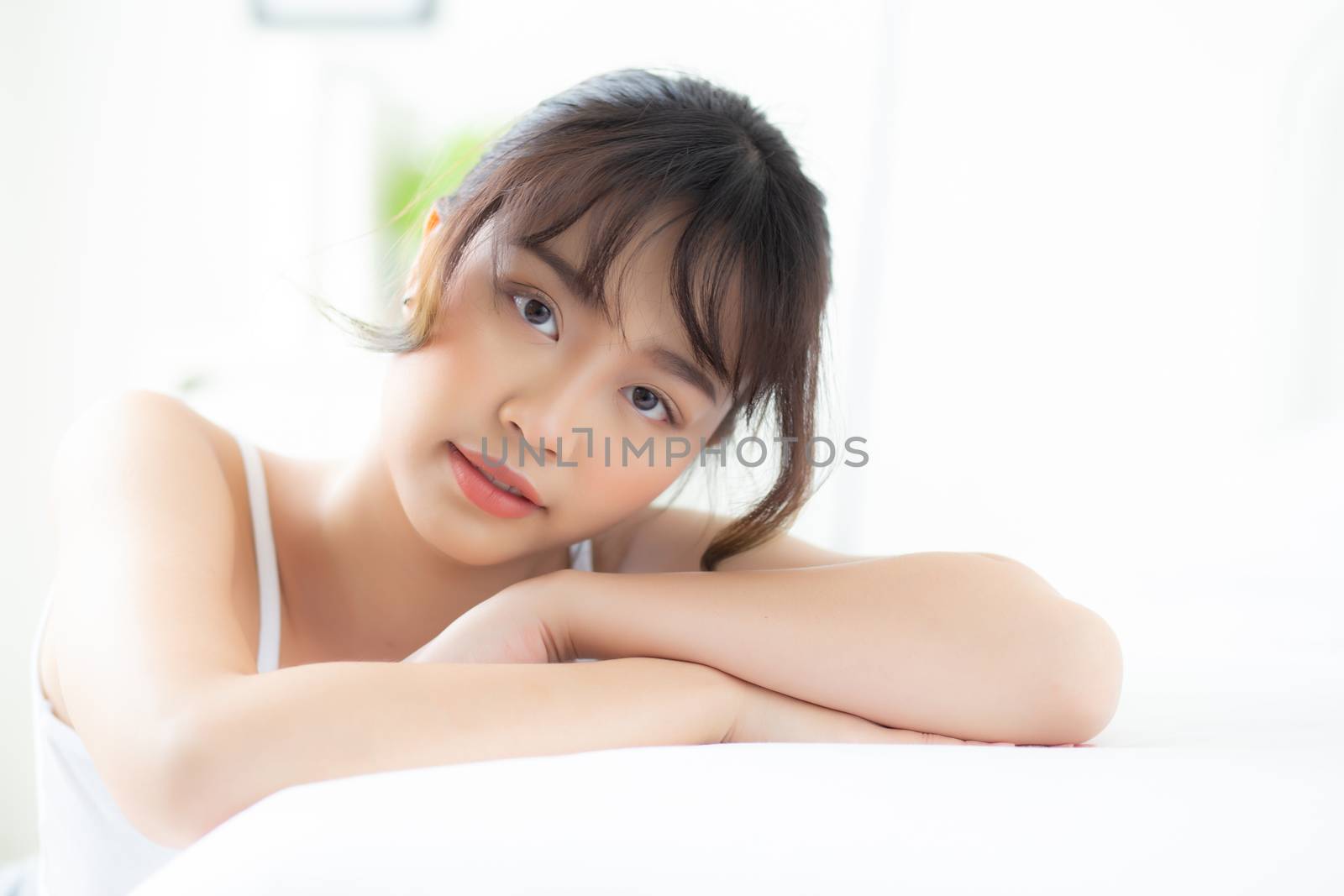 Lifestyle beautiful portrait young asian woman relax lying sleep and smile while wake up with sunrise at morning, girl with happy and fun in the bedroom, health and wellness concept.