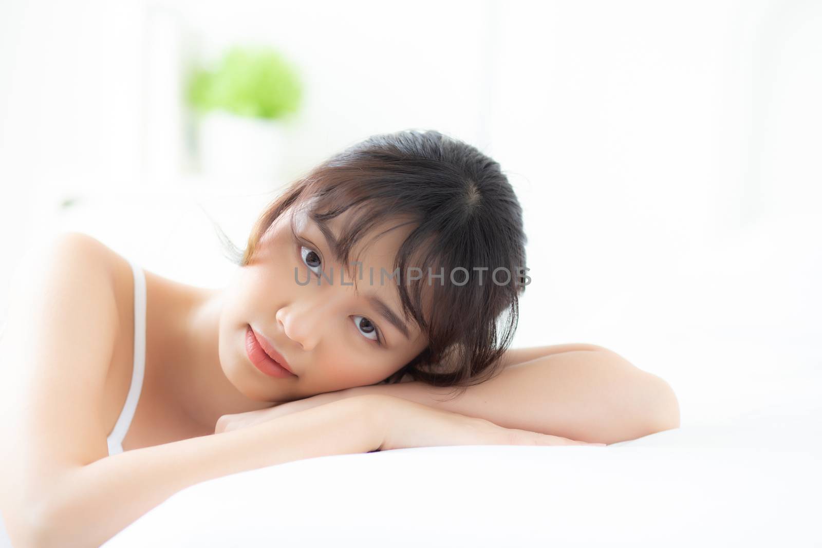 Lifestyle beautiful portrait young asian woman relax lying sleep and smile while wake up with sunrise at morning, girl with happy and fun in the bedroom, health and wellness concept.