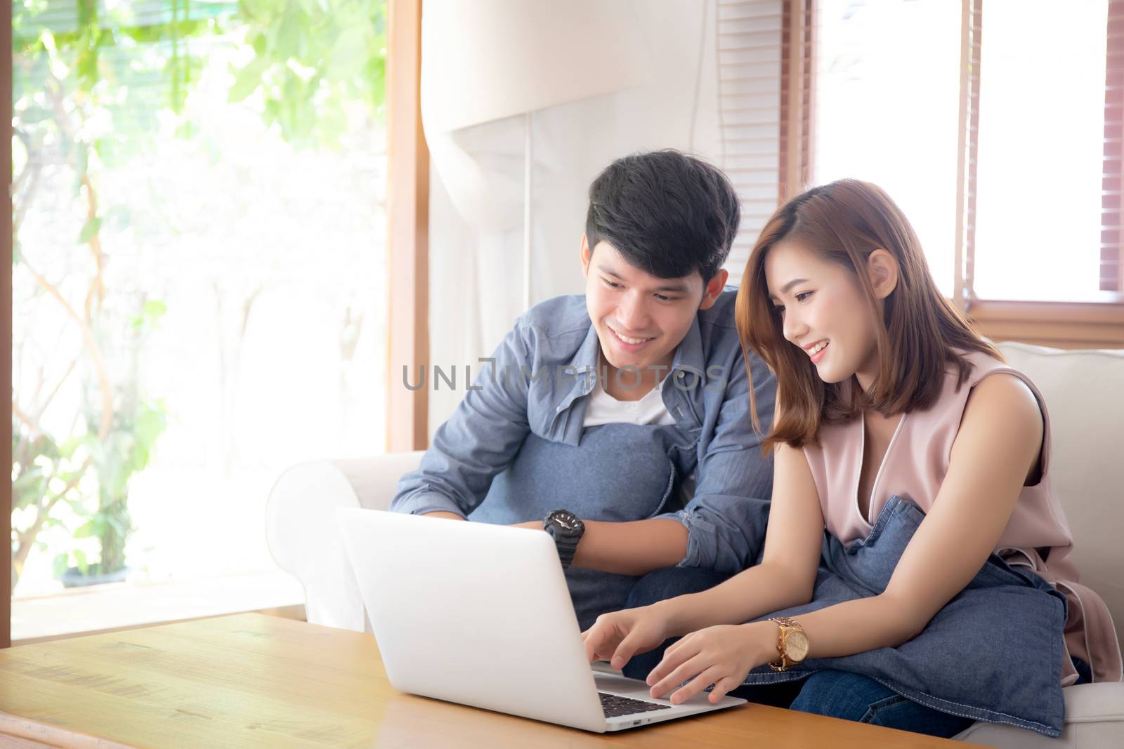 Asian young couple using laptop computer think and searching int by nnudoo