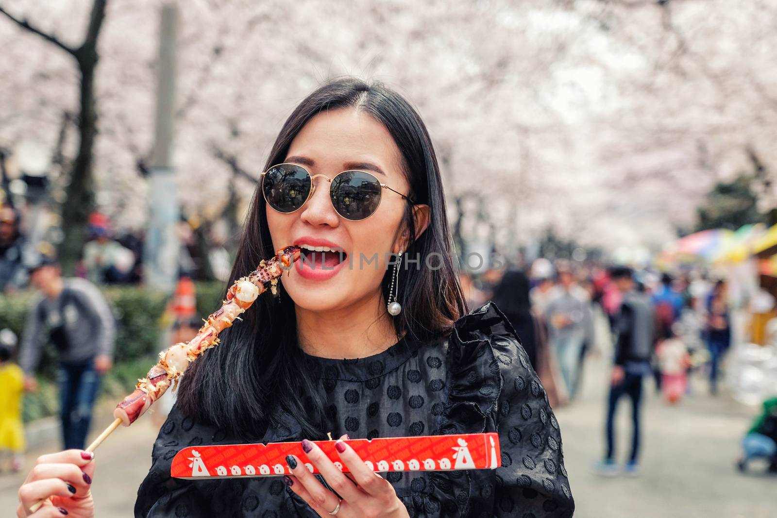 Young woman eating Steamed Octopus Legs at Jinhae Gunhangje Festival street food in Seoul, South Korea