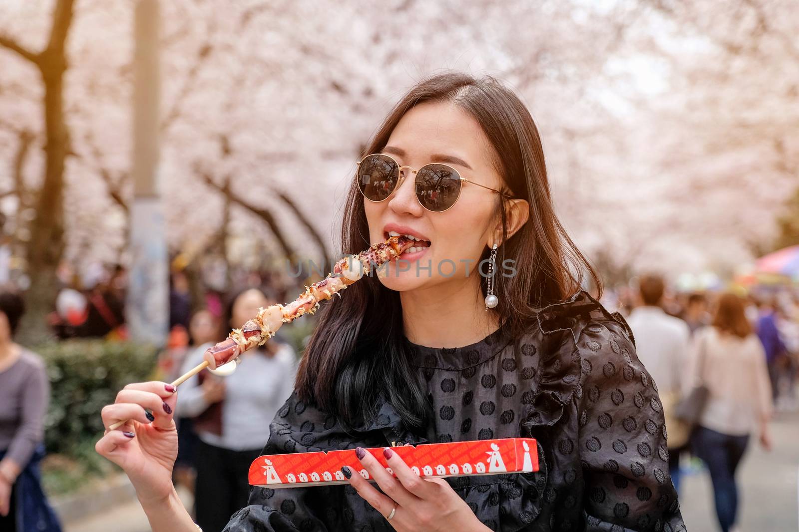 Young woman eating Steamed Octopus Legs at Jinhae Gunhangje Festival street food in Seoul, South Korea