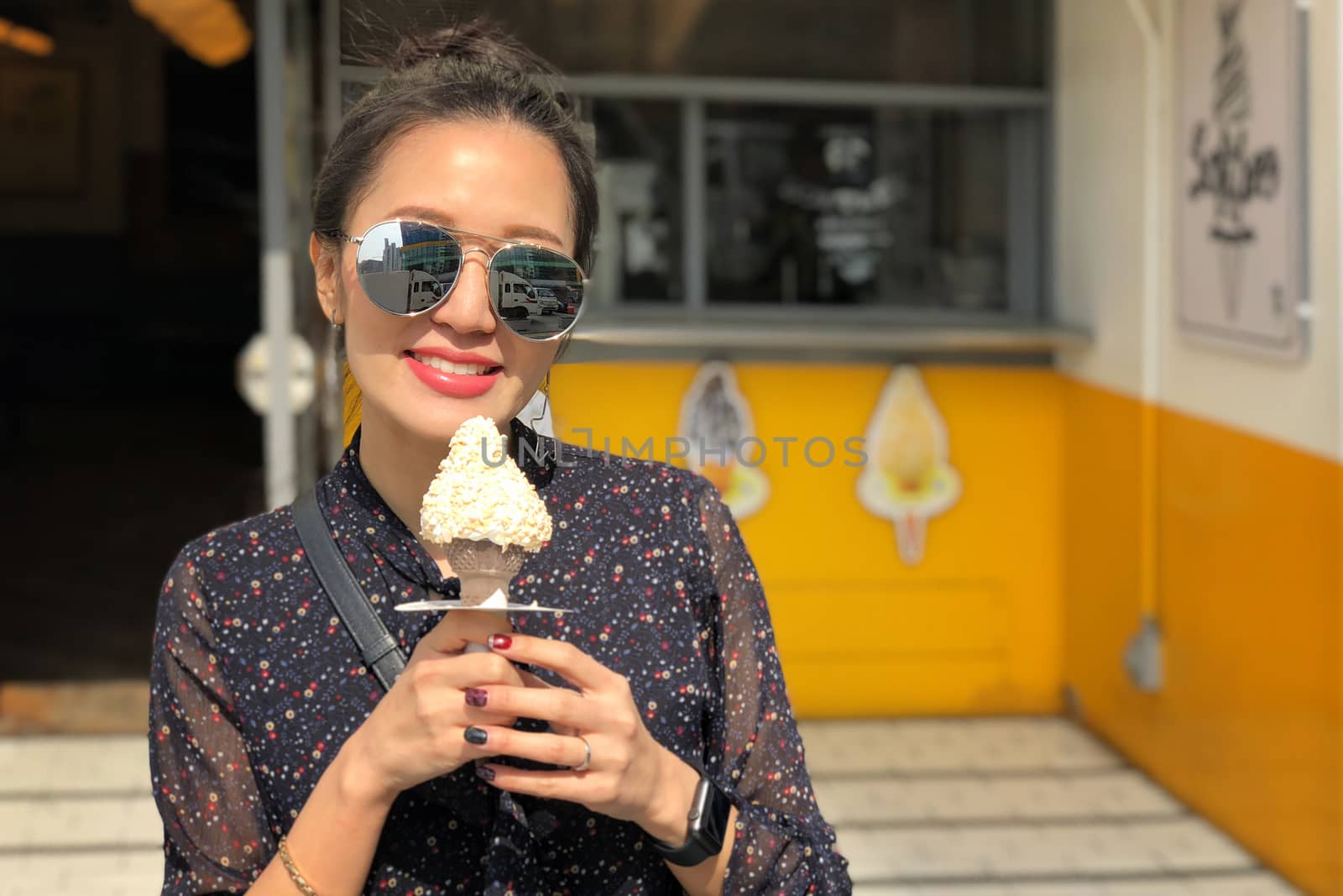 Outdoor closeup fashion portrait of young woman with sunglasses eating ice cream in summer hot weather in Seoul, Korea