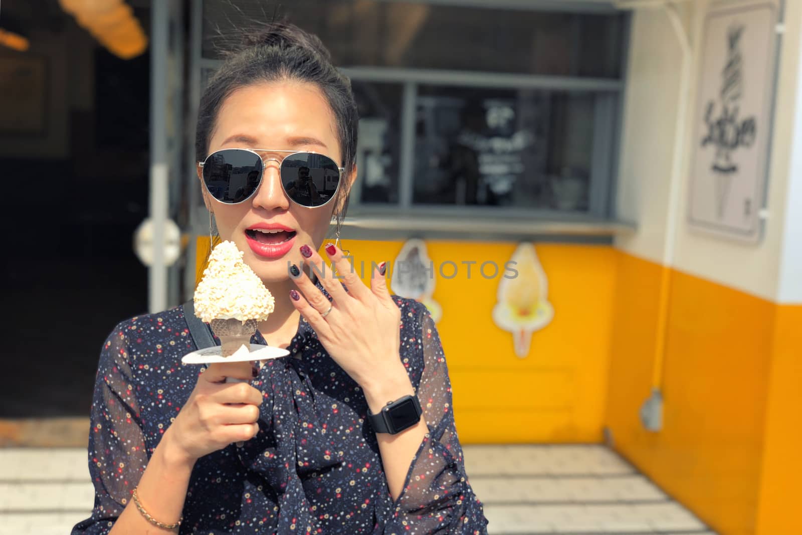 Outdoor closeup fashion portrait of young woman with sunglasses eating ice cream in summer hot weather in Seoul, Korea