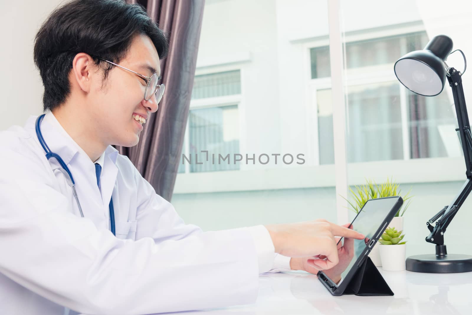 Doctor man smile using black modern smart digital tablet compute by Sorapop