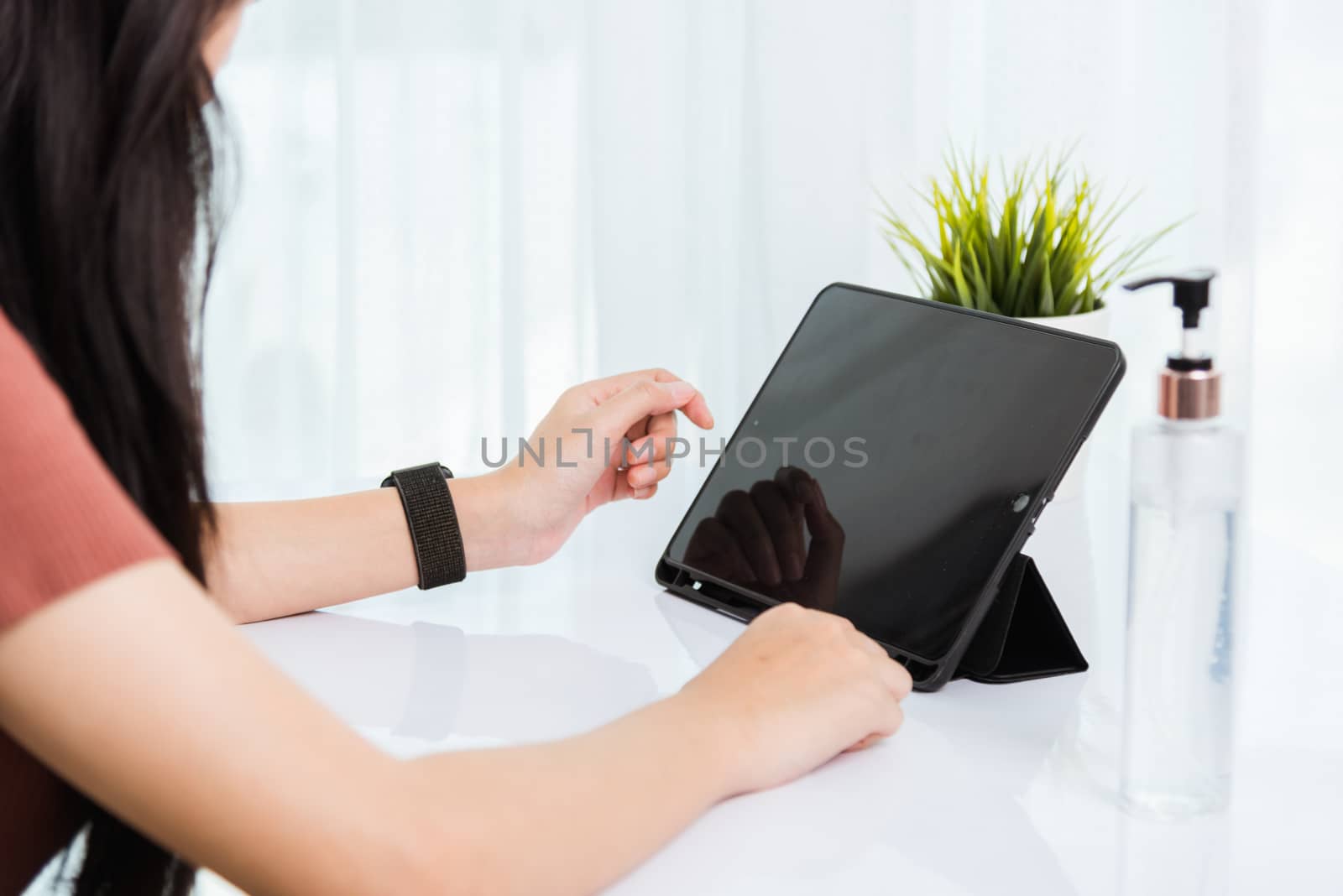 Work from home, Asian young businesswoman wearing face mas protactive video conference call or facetime touch digital smart tablet computer she meeting with colleagues on desk, situation coronavirus