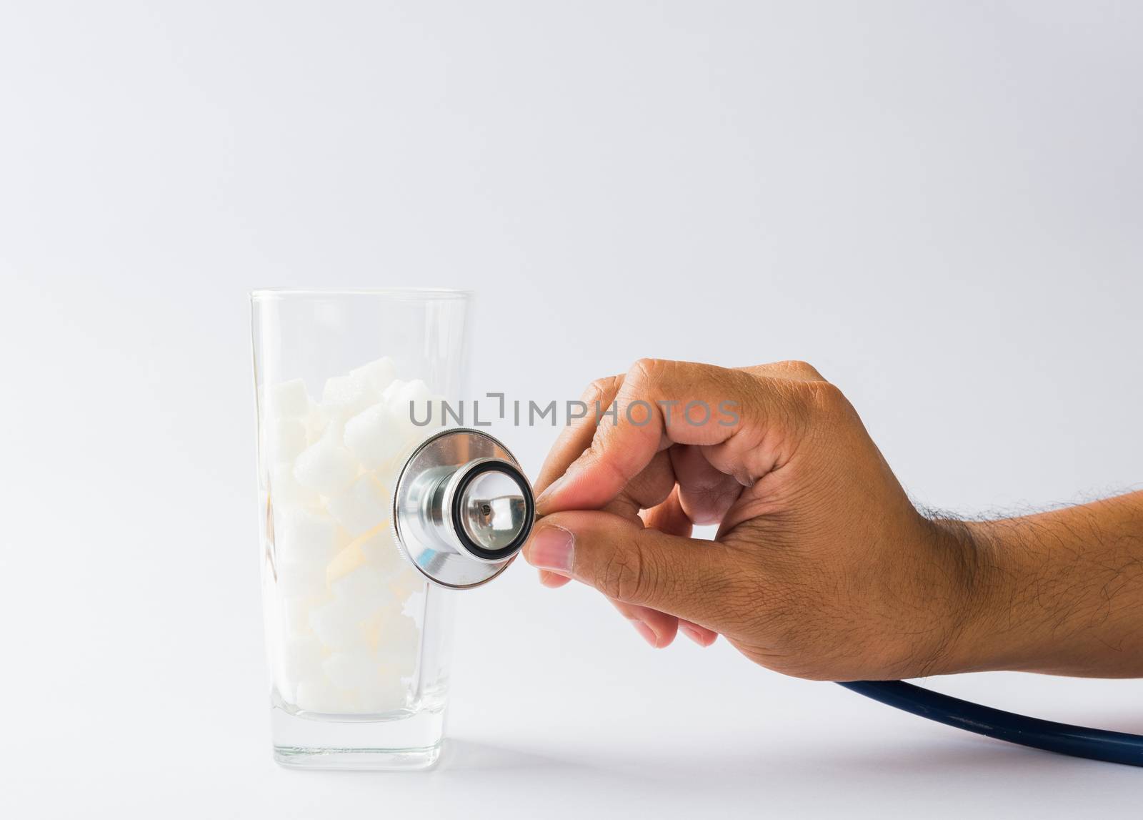 Hand of doctor hold stethoscope check on glass full of white sug by Sorapop