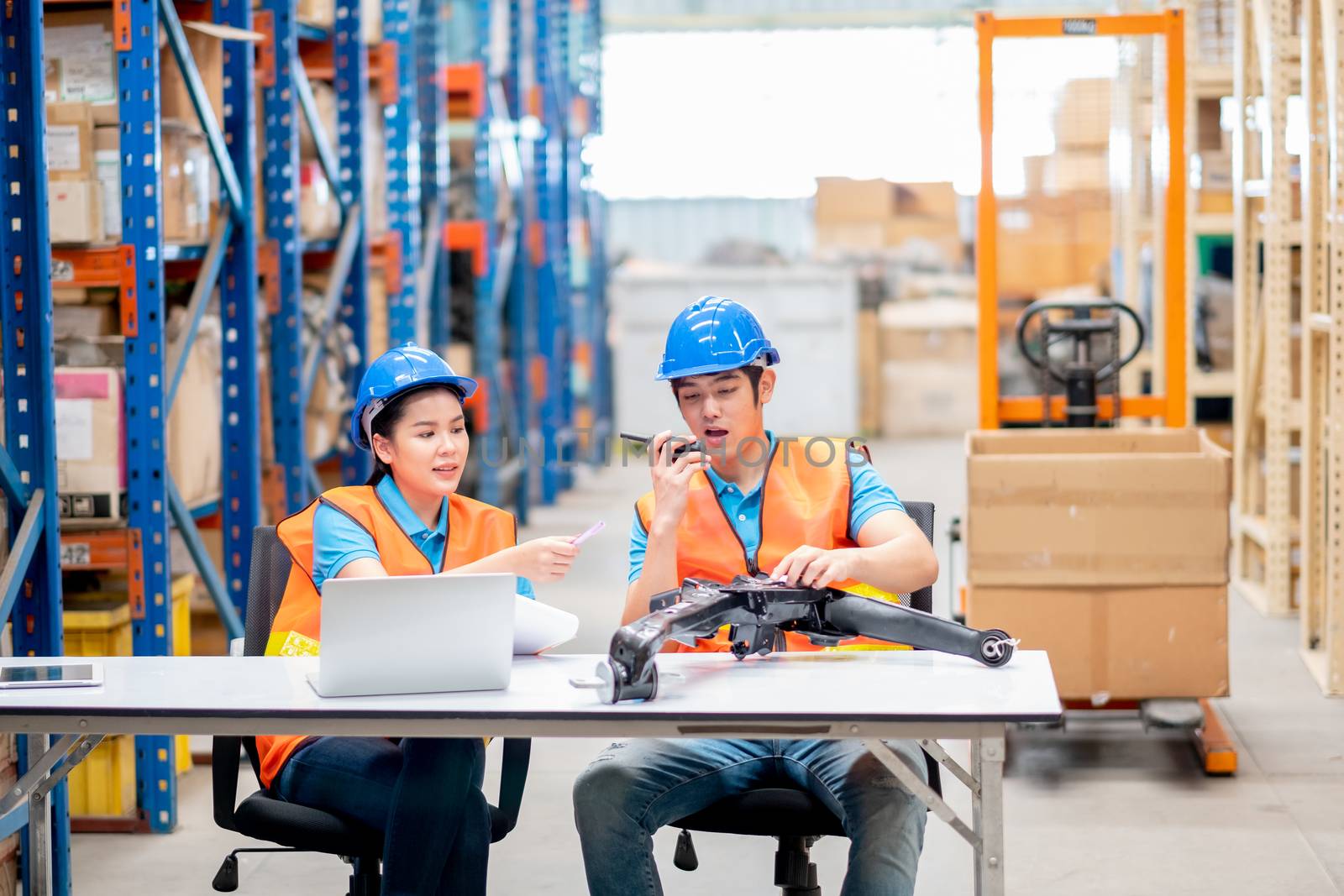 Warehouse man and woman or factory workers sit on chairs and discuss together about stock of automotive parts in workplace area. Concept of good management and happiness in industrial business.