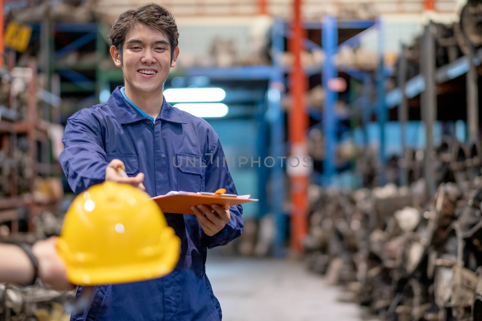 Portrait of factory man with smiling and action of receive hardhat for safety in automotive parts workplace area. Concept of good management and support system for industrial business.