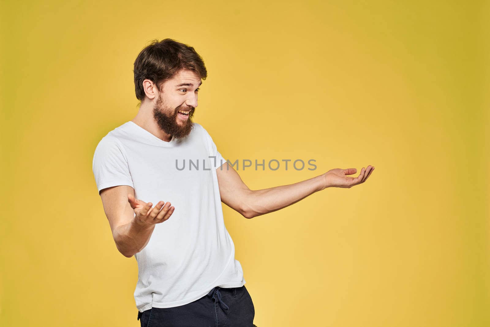 Man gesturing with hands emotions lifestyle white t-shirt yellow isolated background. High quality photo