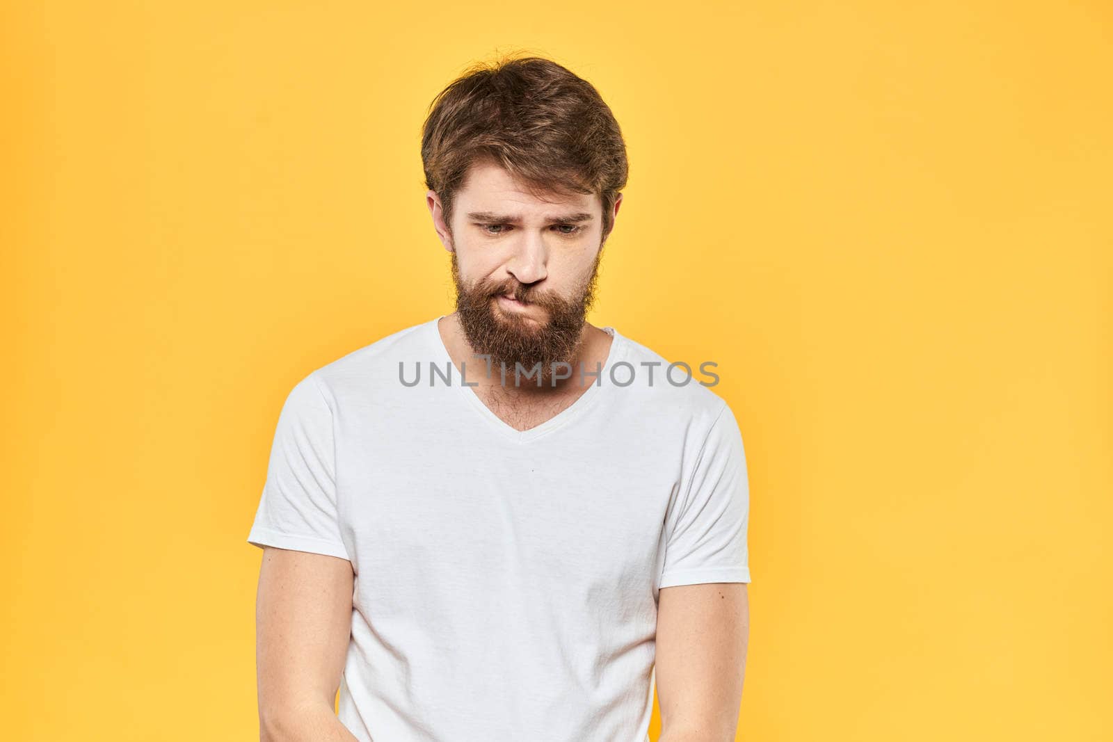 Bearded man in a white T-shirt gestures with his hands emotions studio yellow background by SHOTPRIME