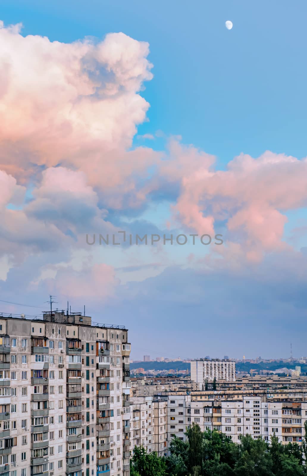High buildings in the Obolon district of Kiev, Ukraine, near the Minska metro station. Big pink clouds in the sky, and the Moon