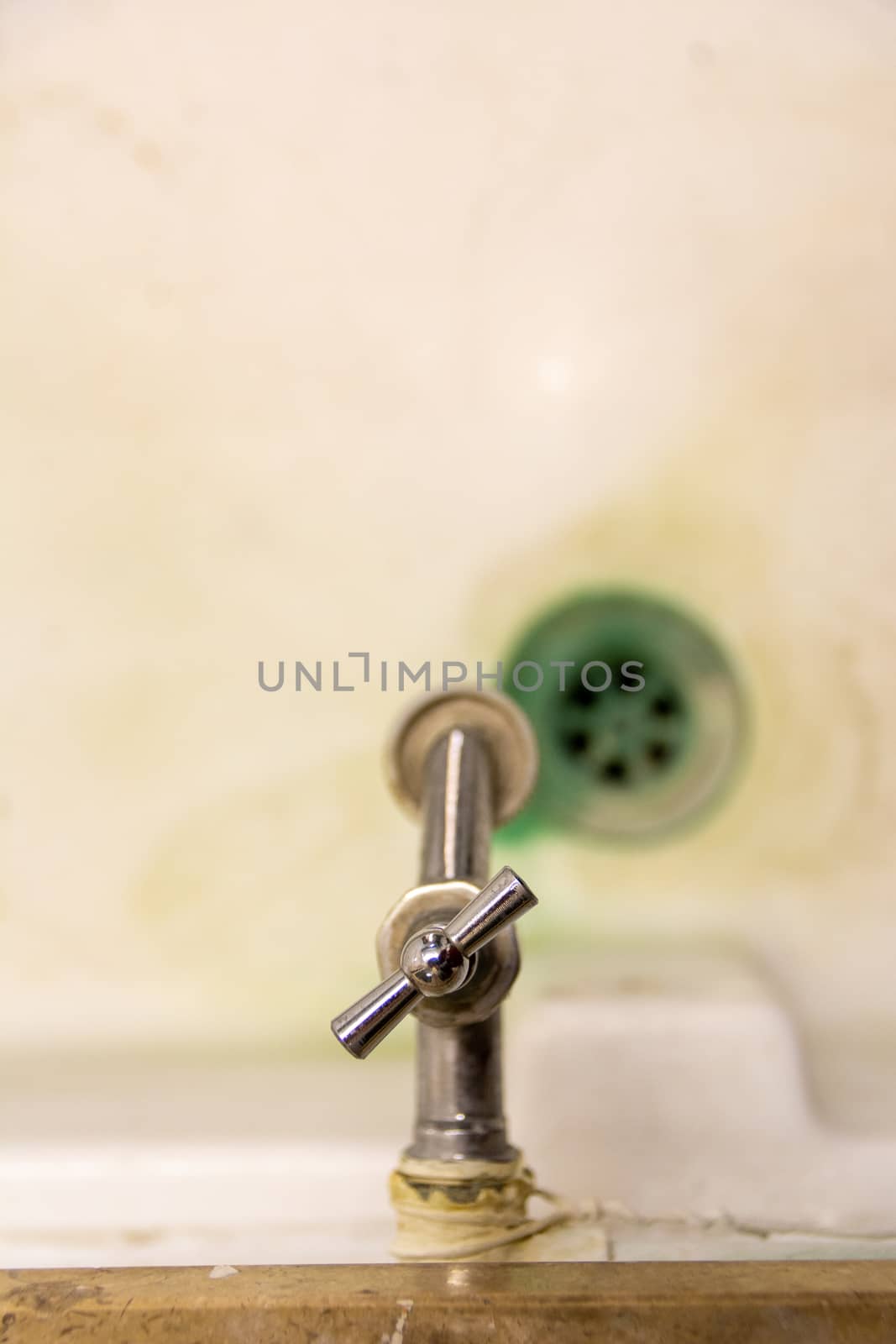 old and dirty empty sink stone with water tap drain and faucet. Selective focus, blurry background. by kb79