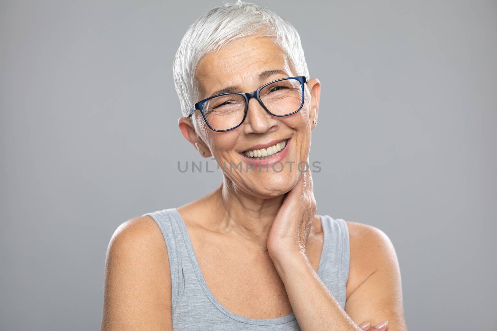 Smiling senior woman with short gray hair and glasses posing in  by adamr