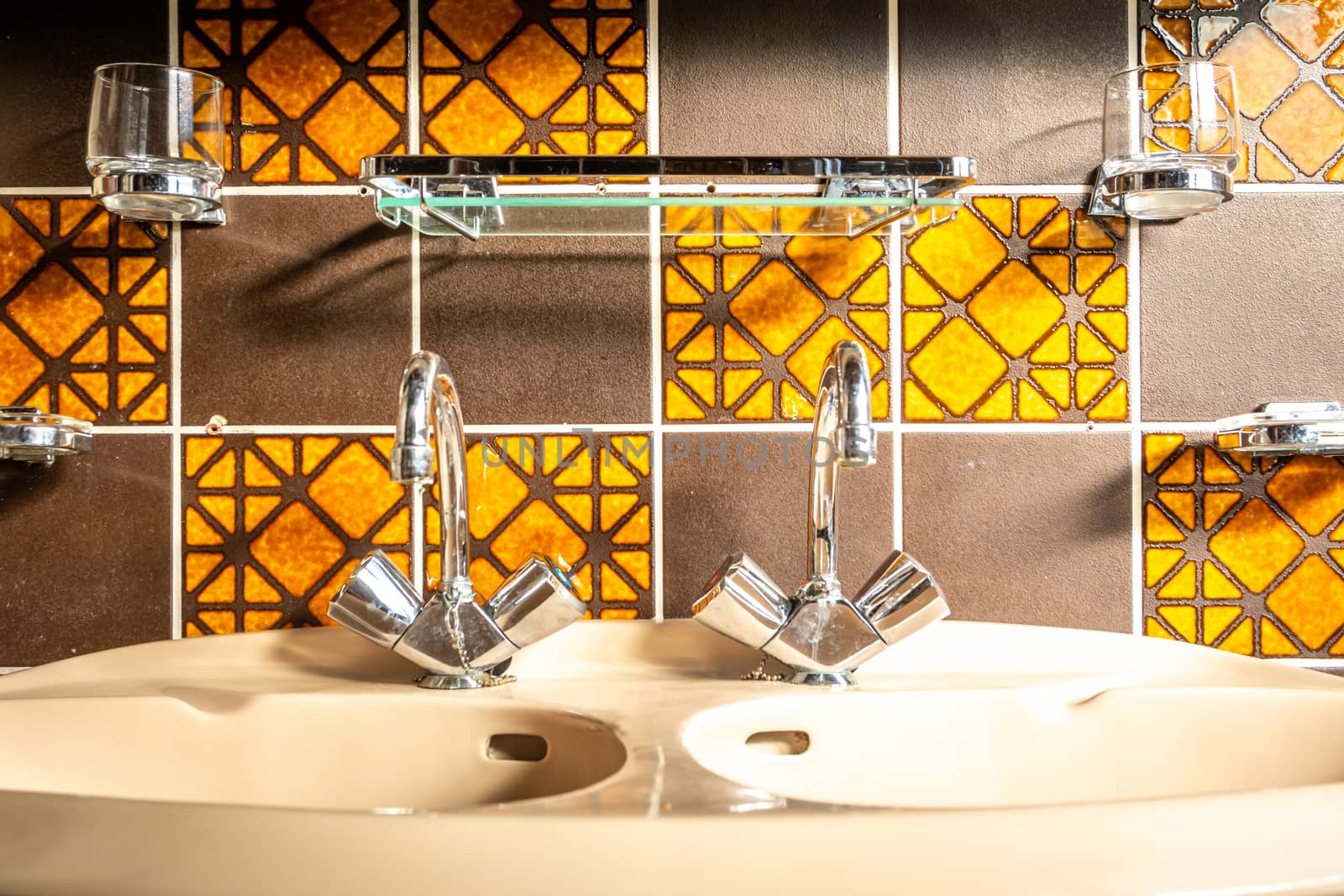 Retro and vintage bathroom sink, with mid century tiles, orange and brown colored.