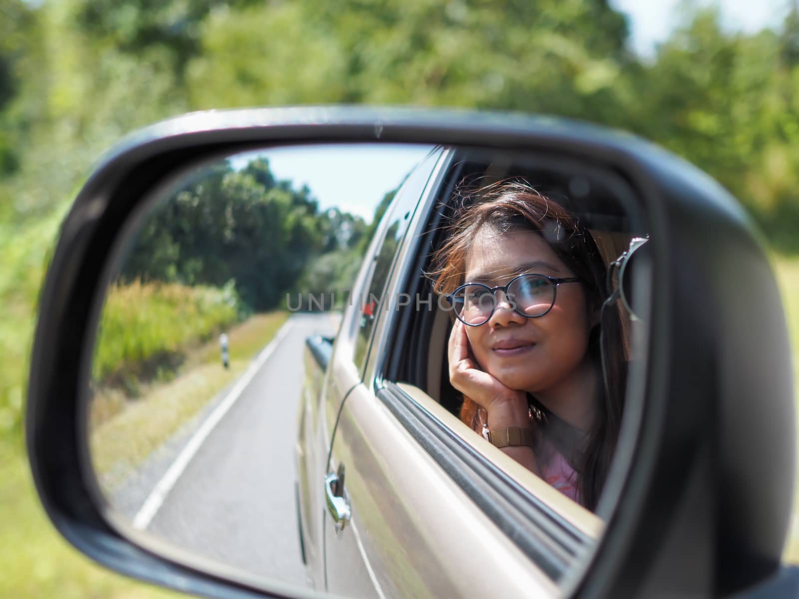 A woman's side-view mirror looking out of the car While driving  by Unimages2527
