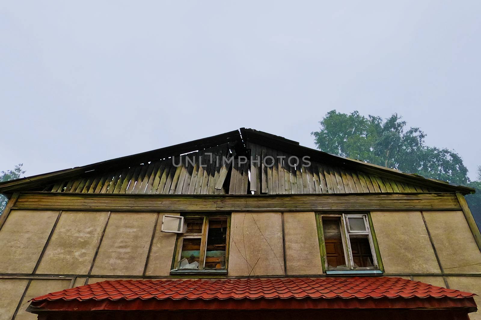 An old house with a burnt roof. View from below. Against a grey sky. by Essffes